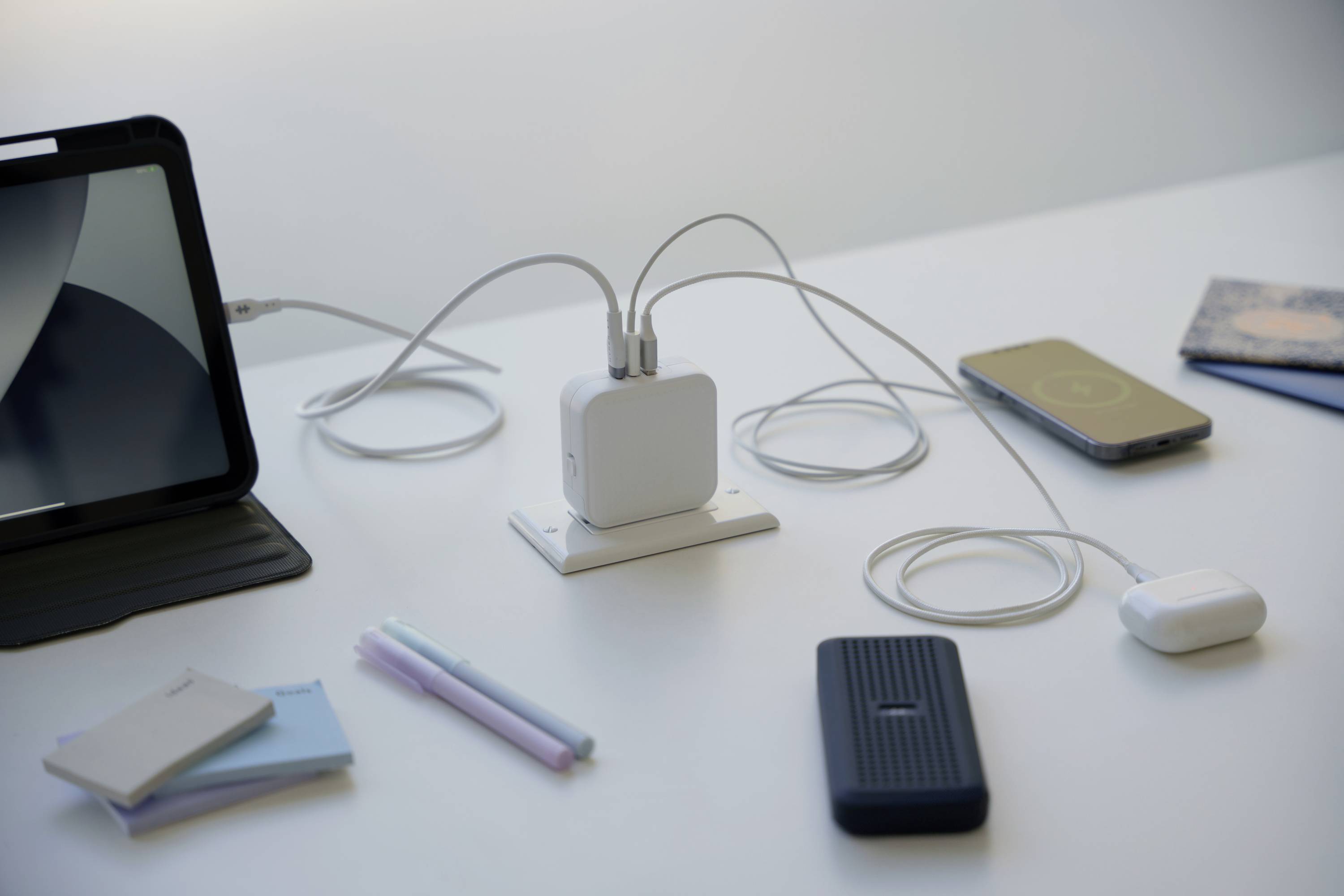 Tablet und Smartphone auf einem Tisch, verbunden mit einem Ladegerät. Ladegerät lädt mehrere Geräte gleichzeitig.