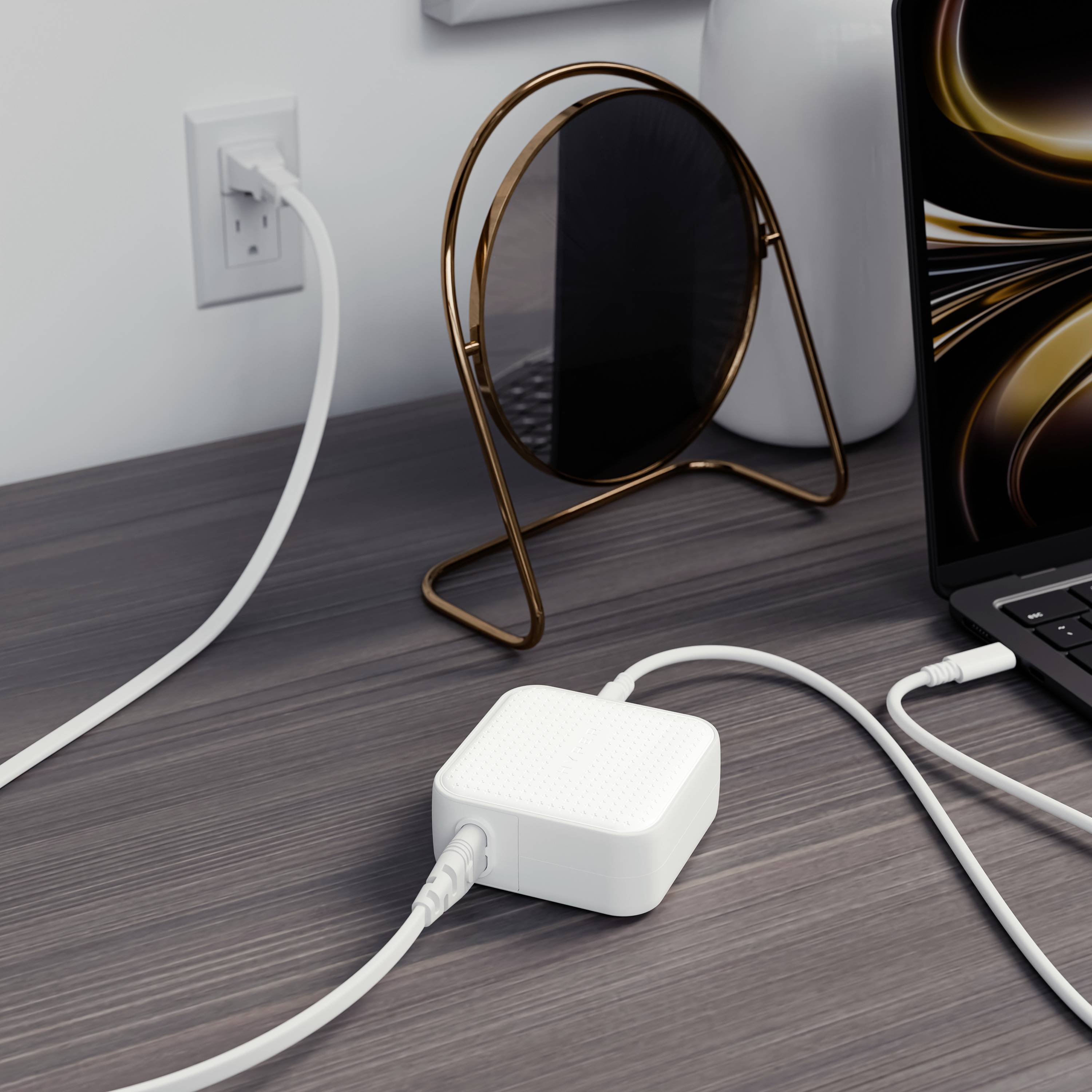 Ein weißer Adapter ist an eine Steckdose angeschlossen. Ein Smartphone-Kabel ist daran eingesteckt. Im Hintergrund ist ein Laptop zu sehen.