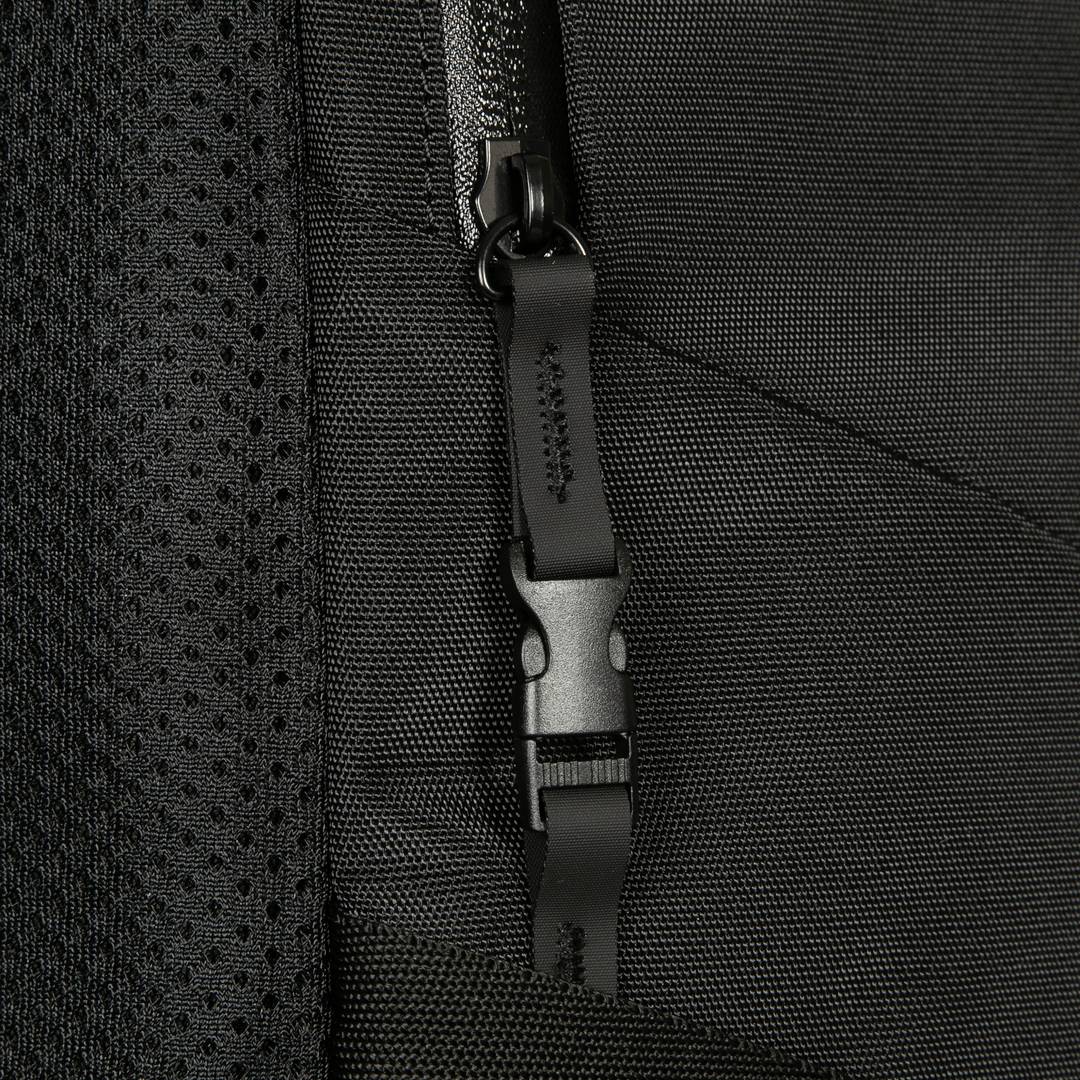 Nahaufnahme eines schwarzen Rucksacks mit Reißverschluss. Deutliche Textur und Zipper-Detail sichtbar.