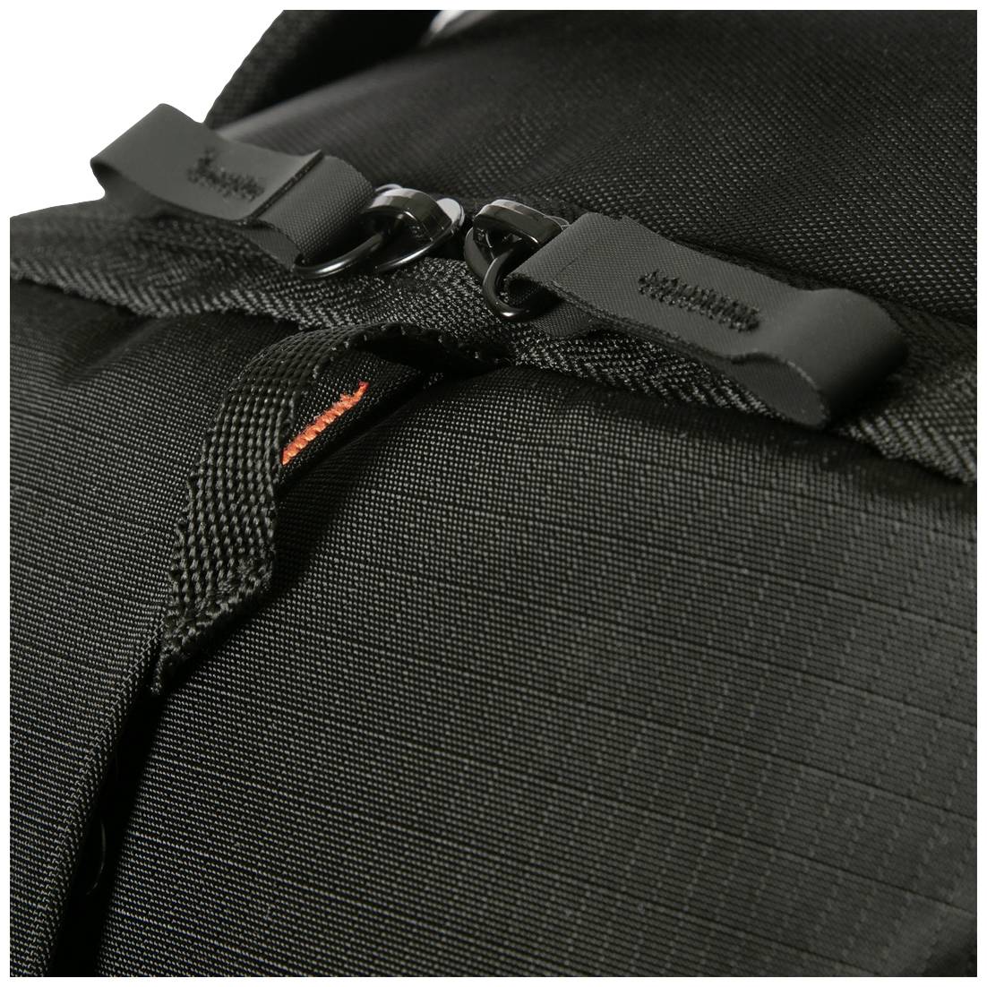 Nahaufnahme eines schwarzen Rucksacks mit Reißverschlüssen und robustem Stoff, Fokus auf die zwei schwarzen Reißverschlussgriffe.