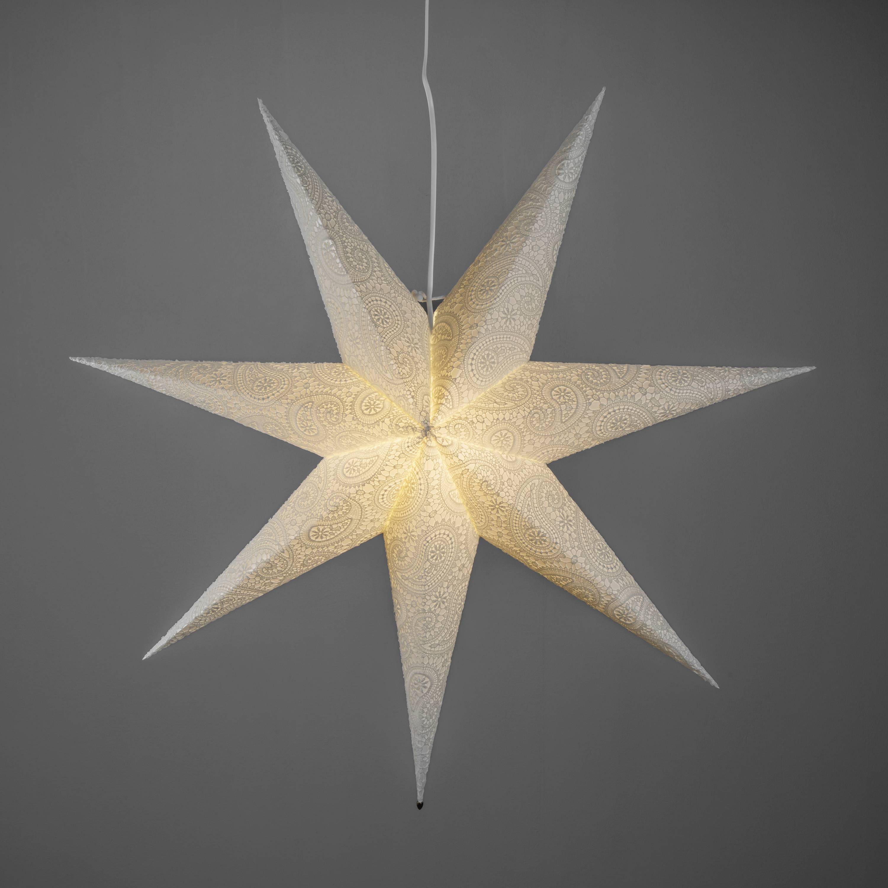 Ein leuchtender Papierstern mit feinem Muster hängt von der Decke und strahlt ein warmes Licht aus.