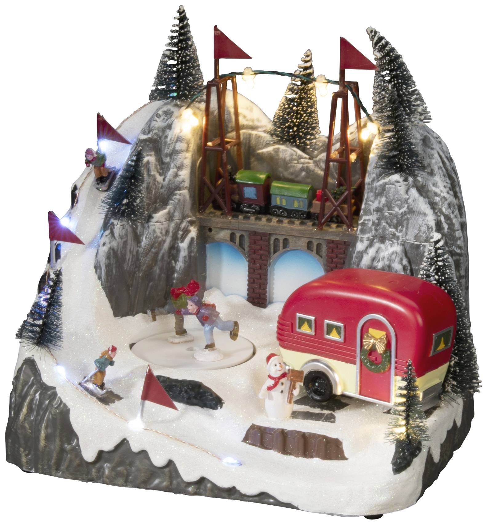 Eine Winterlandschaft mit Miniatur-Eisenbahn, Schlittschuhläufer, rotem Wohnwagen, Tannen und Schneemann auf schneebedecktem Berg.