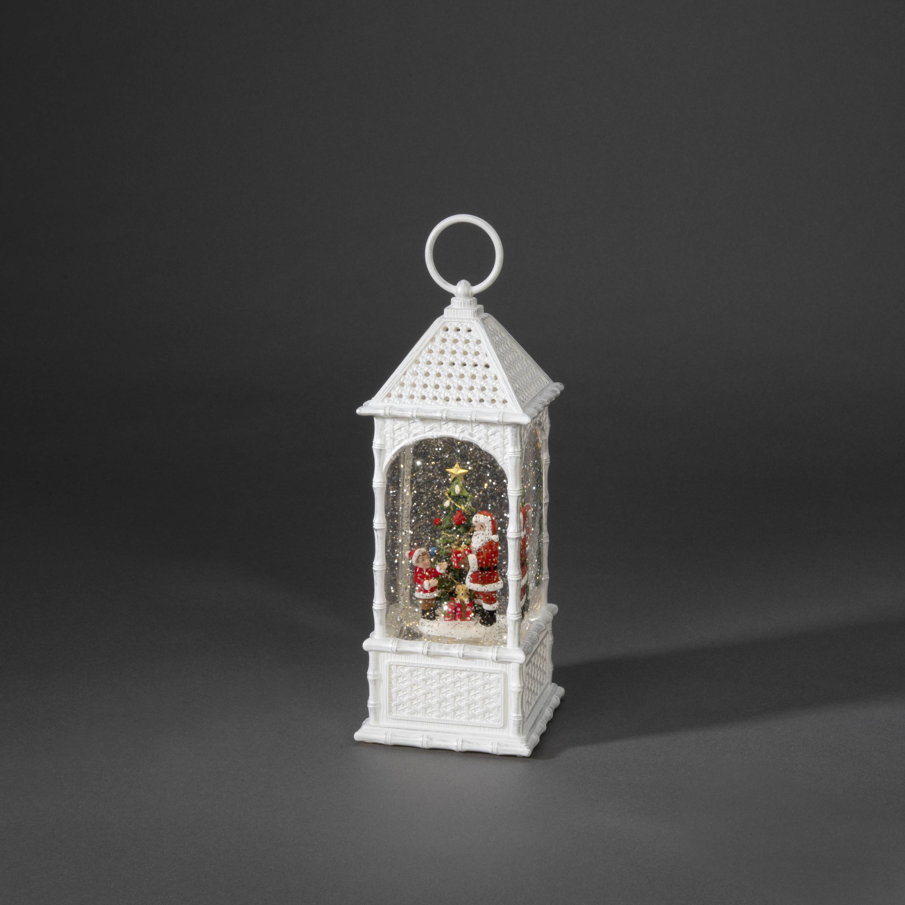 Eine weiße Laterne mit einer weihnachtlichen Schneekugel im Inneren, zeigt einen Weihnachtsmann mit Geschenken und Schnee.