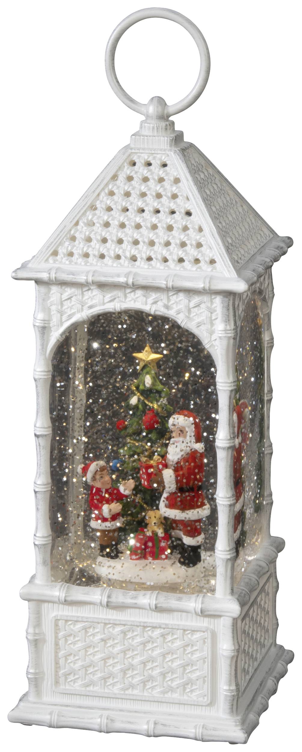 Weiße Laterne mit Weihnachtsmann und Kindern, die einen dekorierten Baum bestaunen. Glitzernde Schneeflocken füllen die Szene.