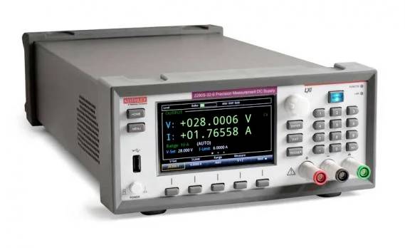 Ein digitales Multimeter zeigt 'V: +028.0006 V' und 'I: +01.76558 A' mit mehreren Knöpfen und Anschlüssen vorne.