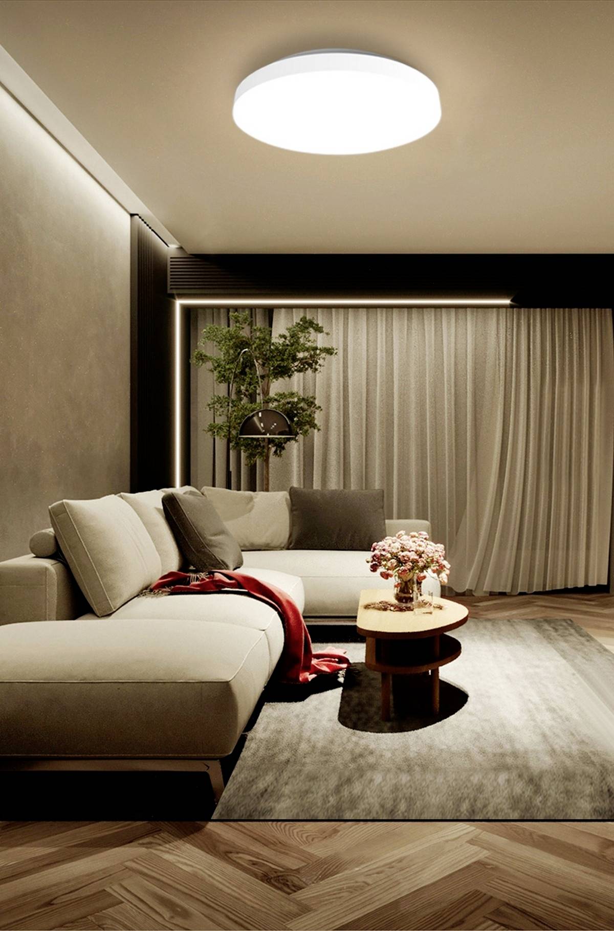 Ein Wohnzimmer mit einem grauen Sofa, einem runden Holztisch und einer modernen Deckenleuchte. Ein rotes Tuch liegt auf dem Sofa.