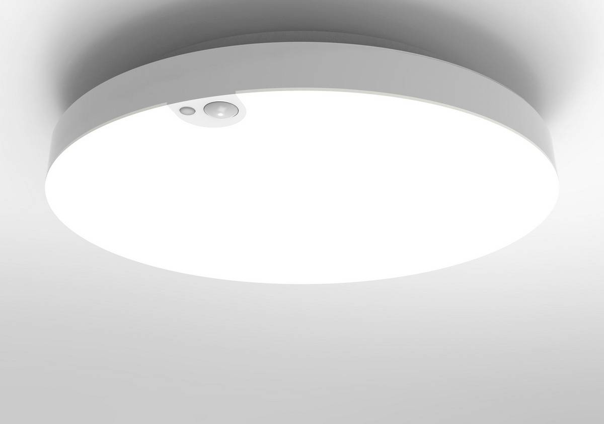 Runde, weiße Deckenlampe mit eingebautem Bewegungssensor leuchtet hell auf einer grauen Decke.