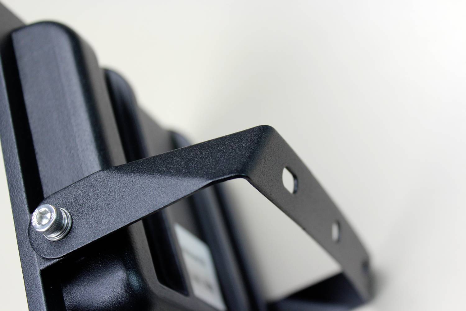 Nahaufnahme eines metallenen Halters mit Befestigungsschrauben, möglicherweise Teil eines Beleuchtungssystems oder einer technischen Vorrichtung.