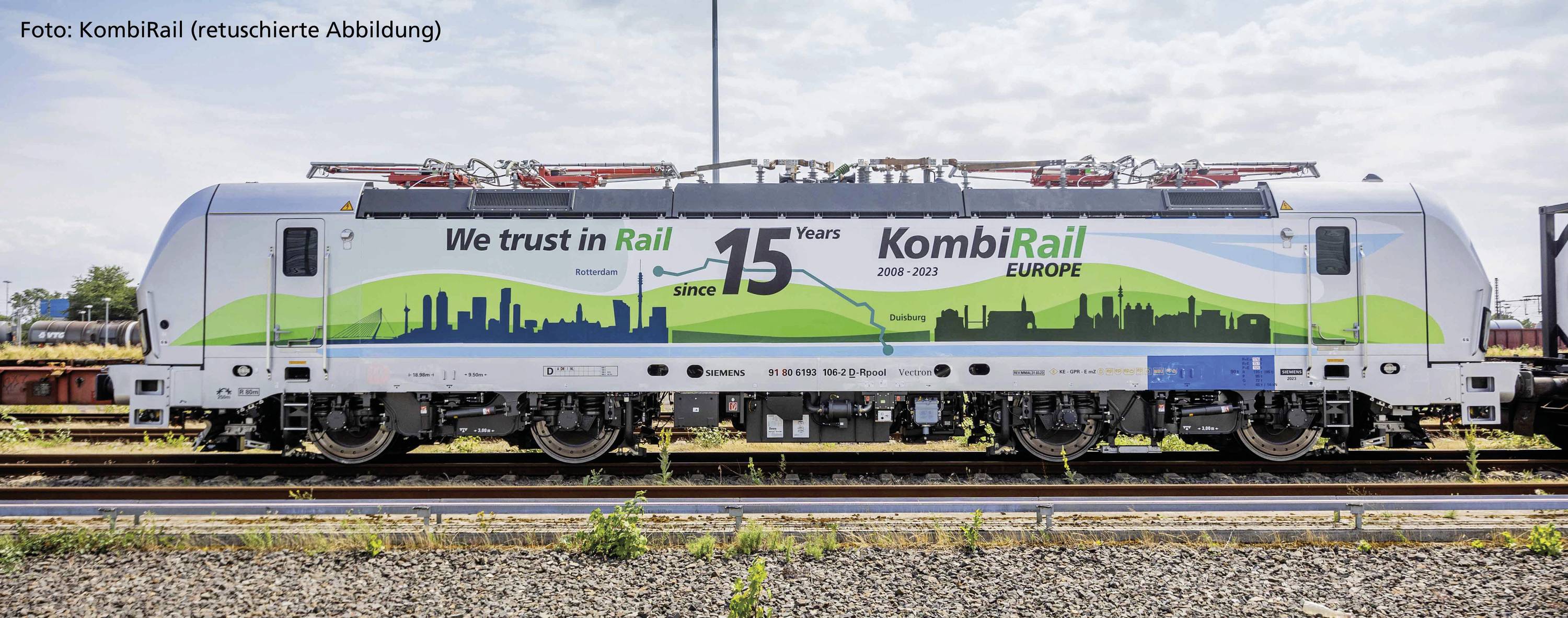 Ein Zug mit der Aufschrift 'We trust in Rail since 15 Years' und 'KombiRail EUROPE'. Im Hintergrund sind Stadt-Silhouetten abgebildet.