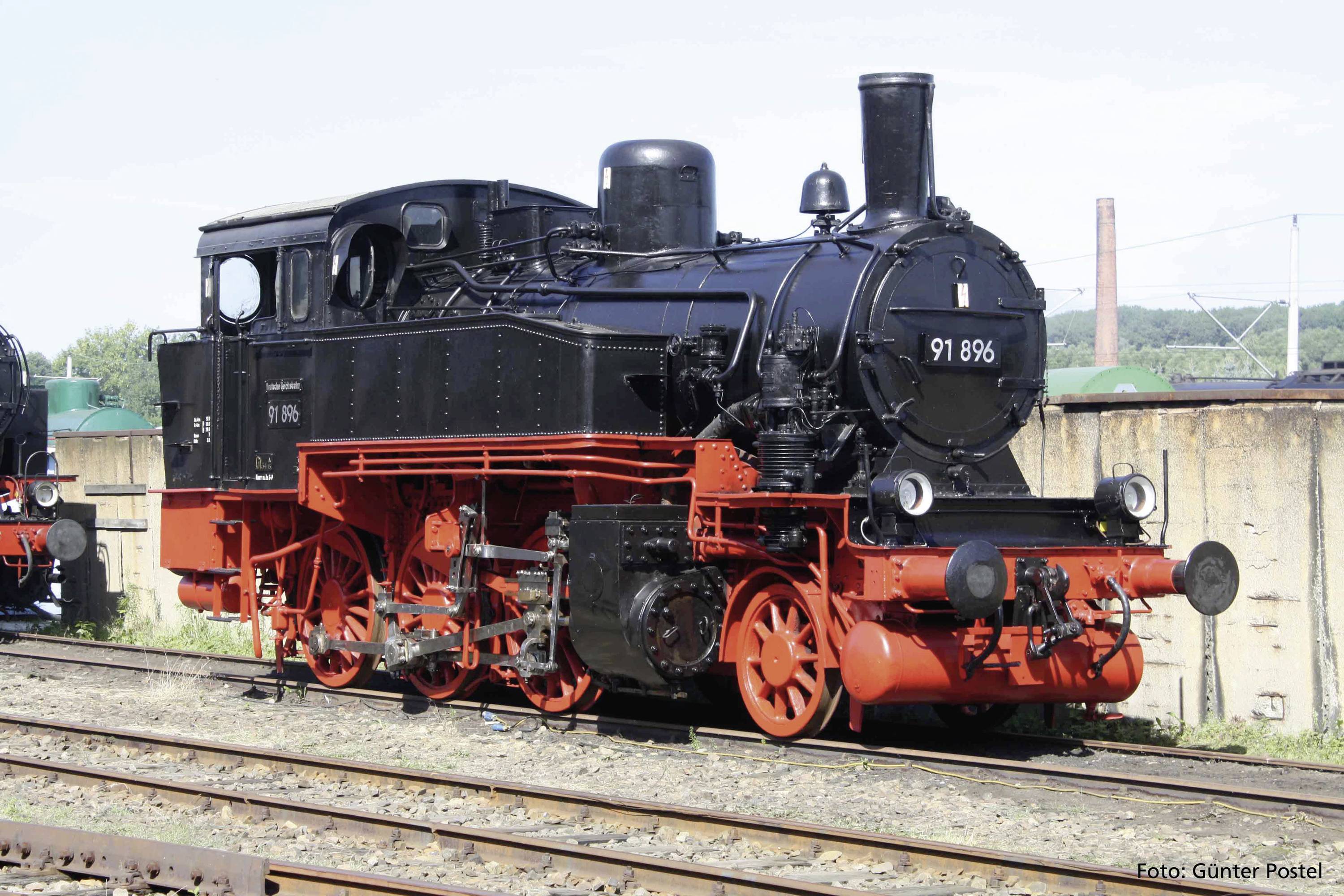 Eine historische Dampflokomotive mit der Nummer '91 896' steht auf Gleisen, schwarze Karosserie mit roten Rädern, outdoor im Sommer.