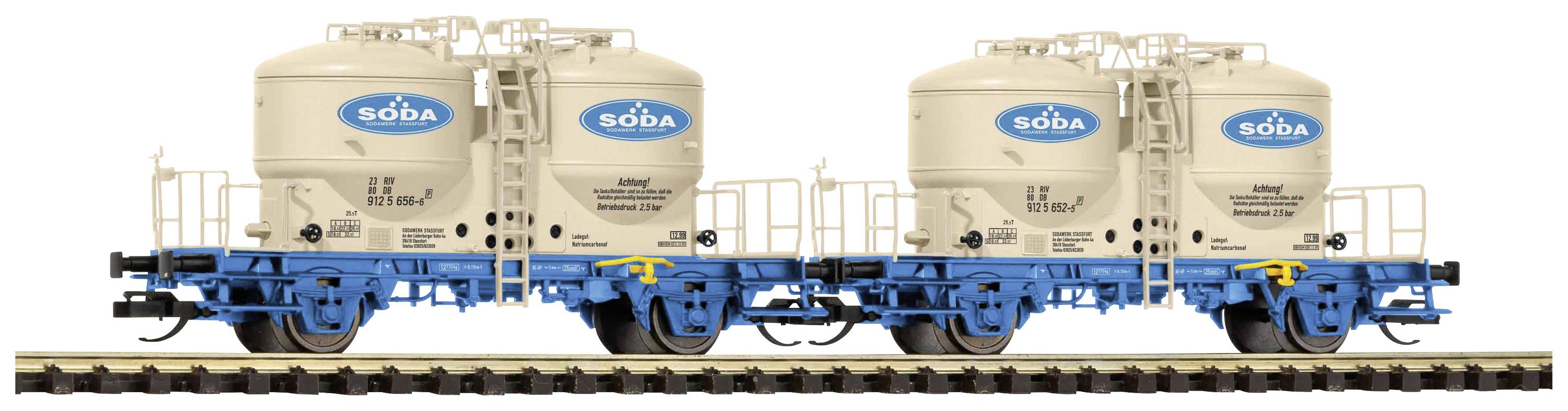 Zwei beige Güterwaggons mit blauen Fahrgestellen auf Eisenbahnschienen, jeweils mit 'Soda'-Logo beschriftet.
