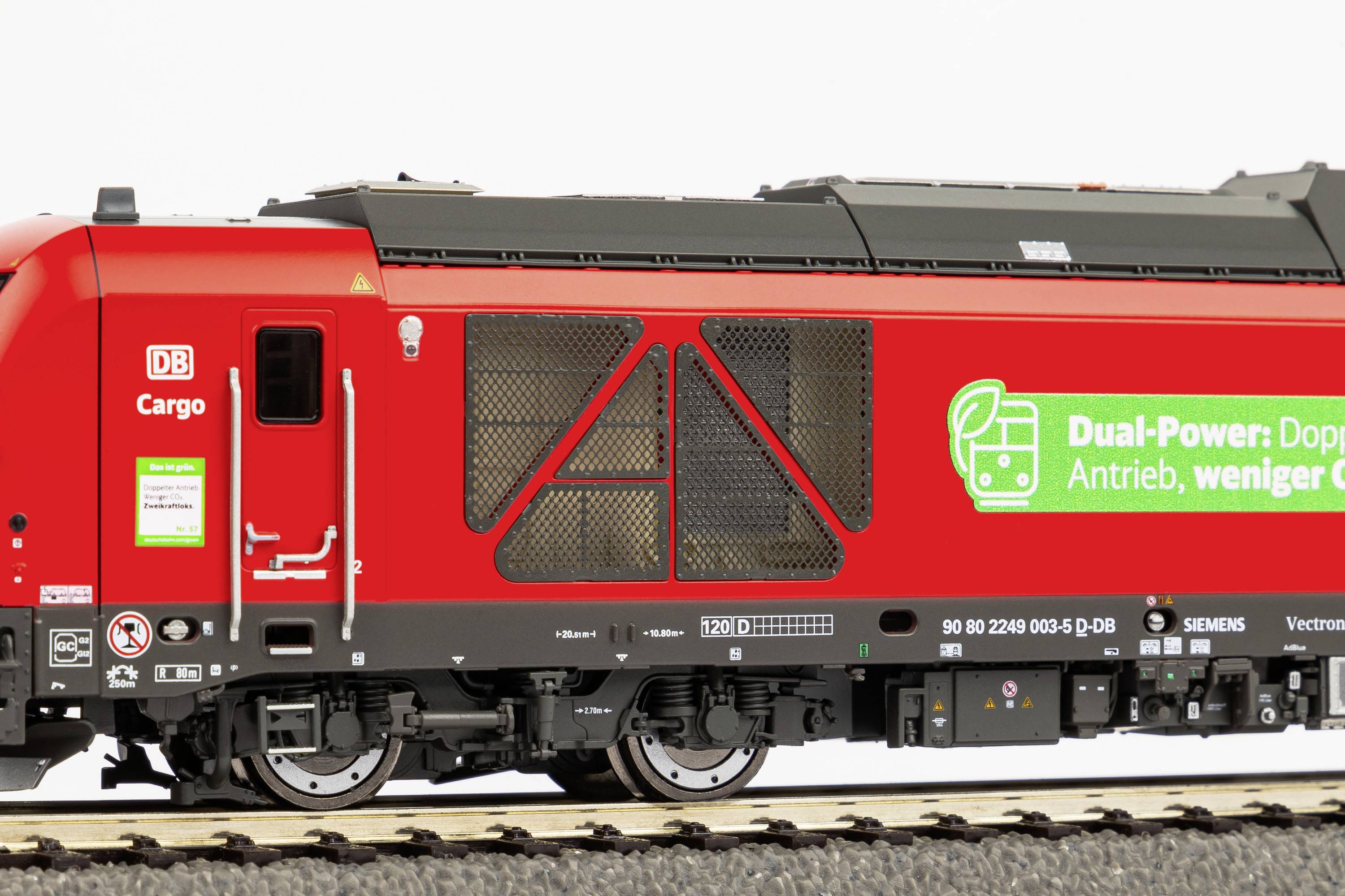 Eine rote Lokomotive mit dem Logo von DB Cargo und dem Slogan 'Dual-Power: Doppelte Antrieb, weniger CO2' auf der Seite.