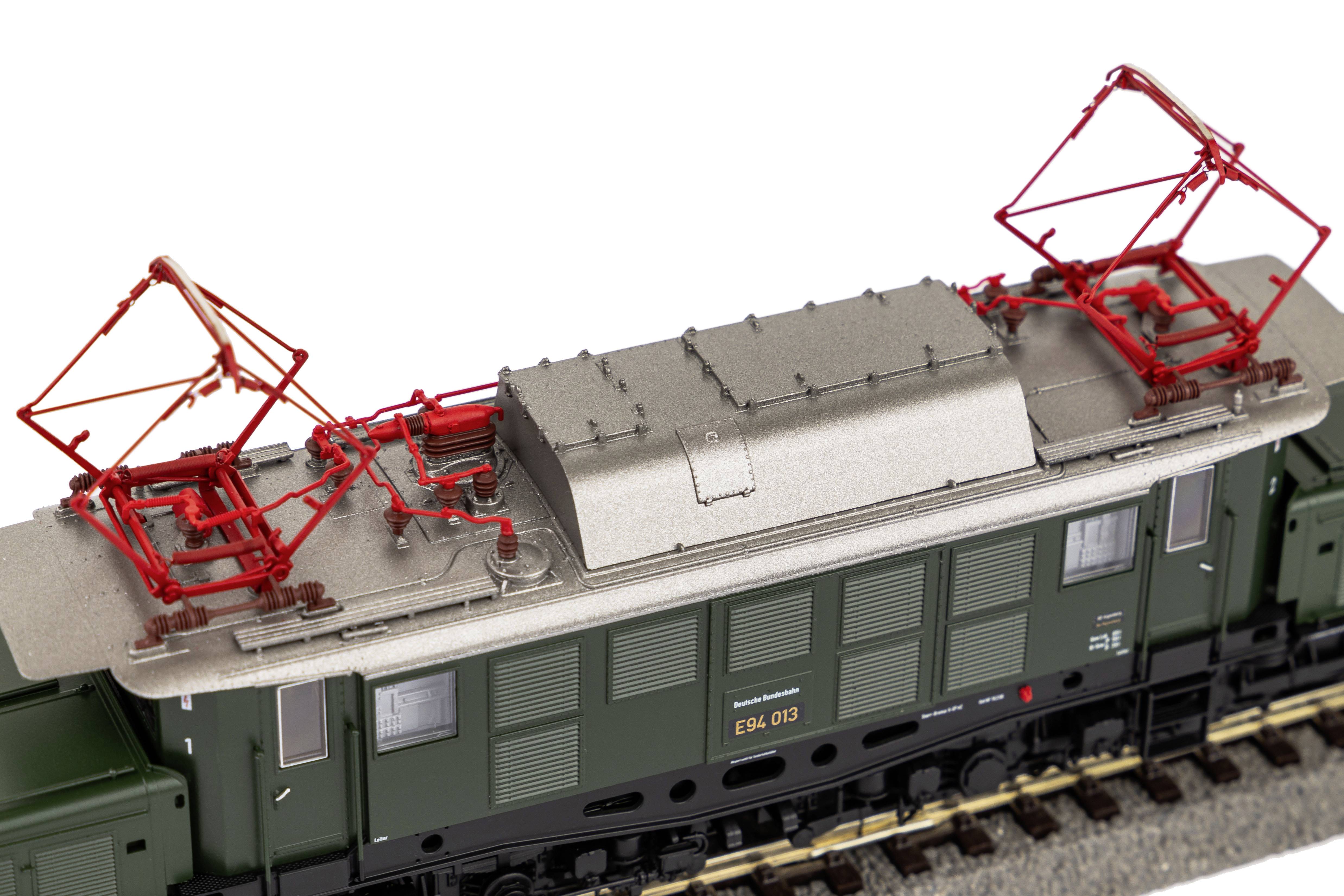 Ein Modell einer grünen Elektrolokomotive mit zwei roten Stromabnehmern auf dem Dach. Detaillierte Nachbildung von Struktur- und Leitungselementen.