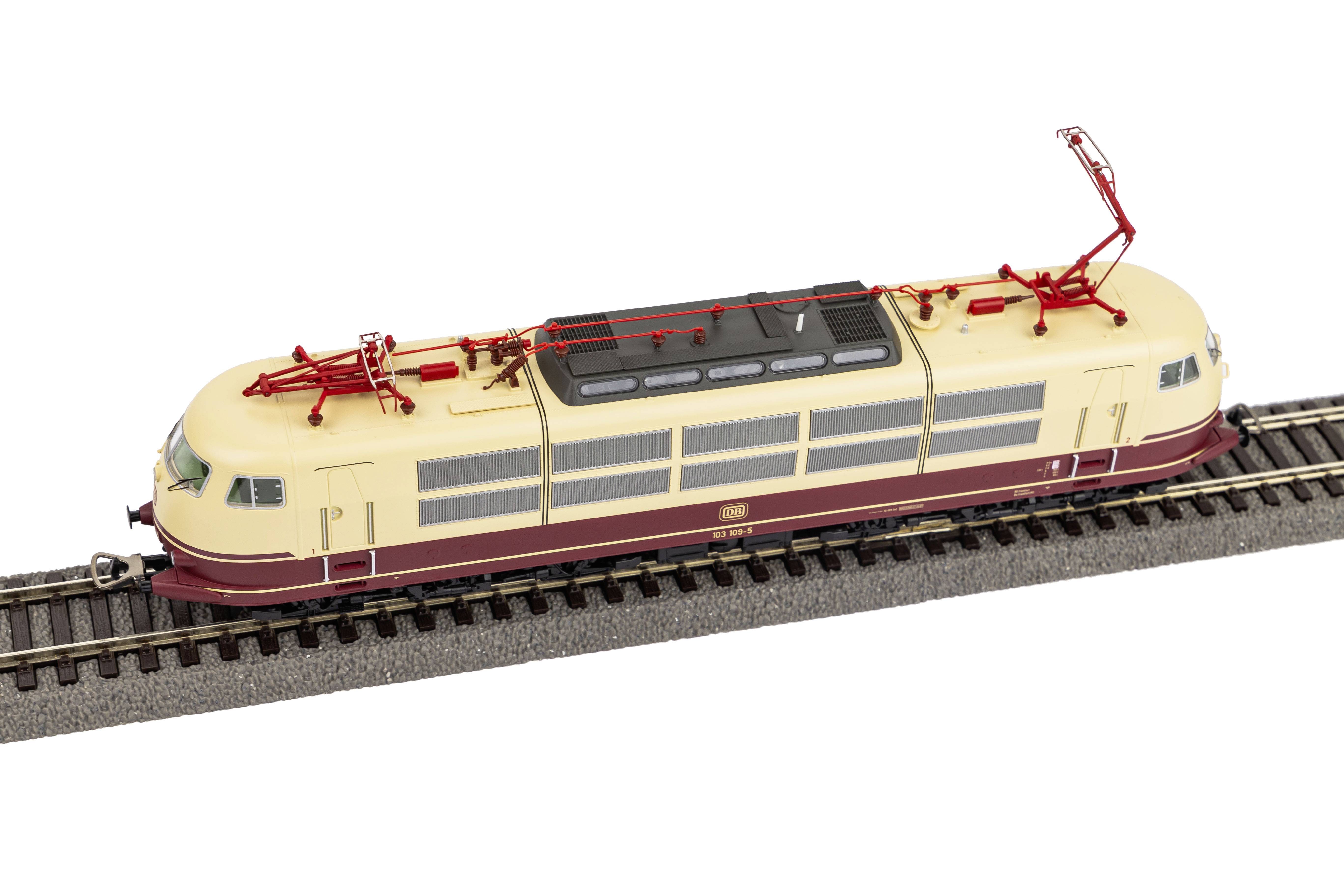 Ein Modellzug einer klassischen Lokomotive auf einem Schienenstück, beige und rot lackiert, mit detaillierten Stromabnehmern.