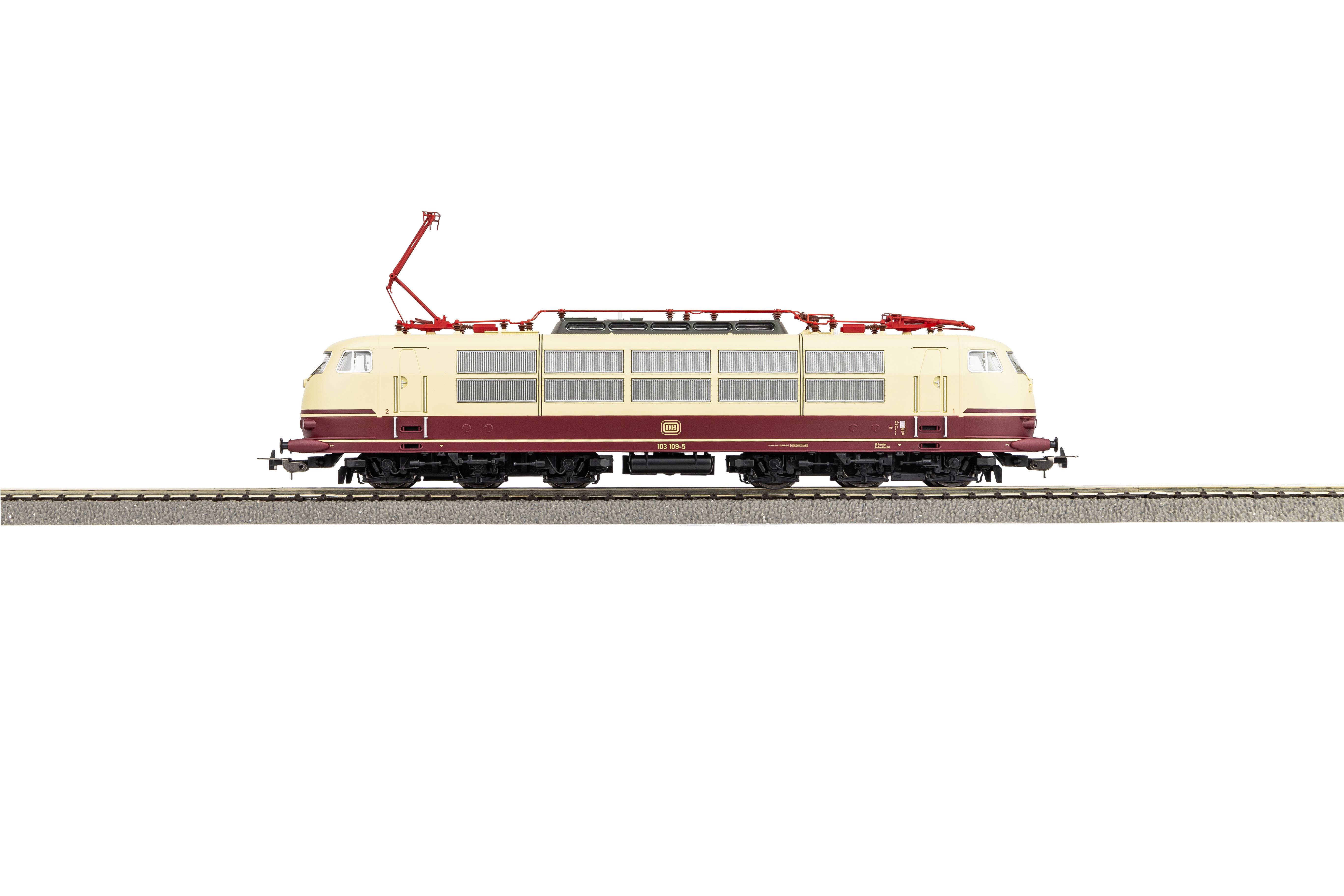 Ein Modellzug, beige mit weinroter Linie, steht auf einem Gleis. Es handelt sich um eine Elektrolokomotive mit einem Stromabnehmer oben.