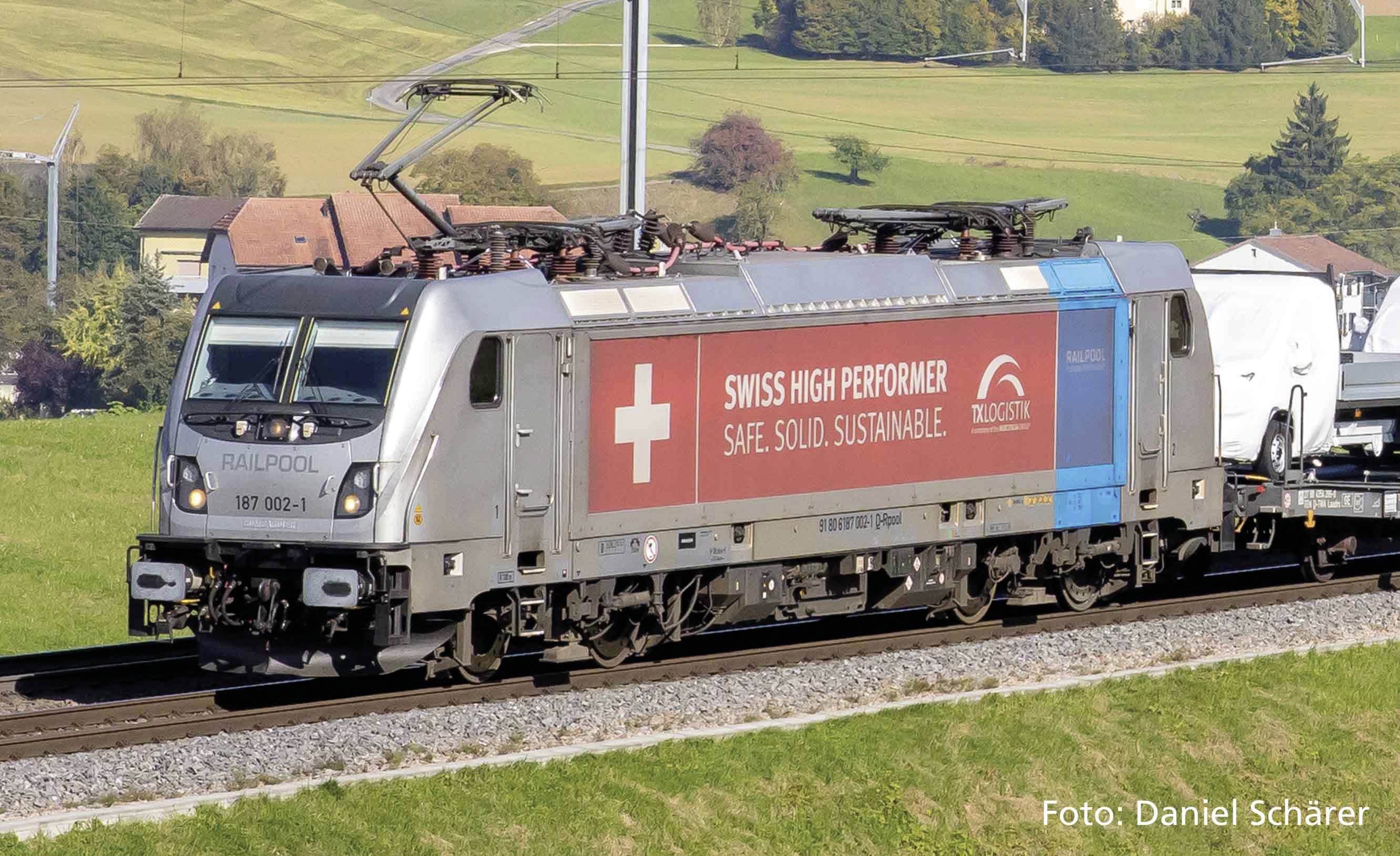Güterzuglokomotive mit 'Swiss High Performer' Banner fährt durch eine ländliche Umgebung. Text wirbt für Sicherheit, und Nachhaltigkeit.