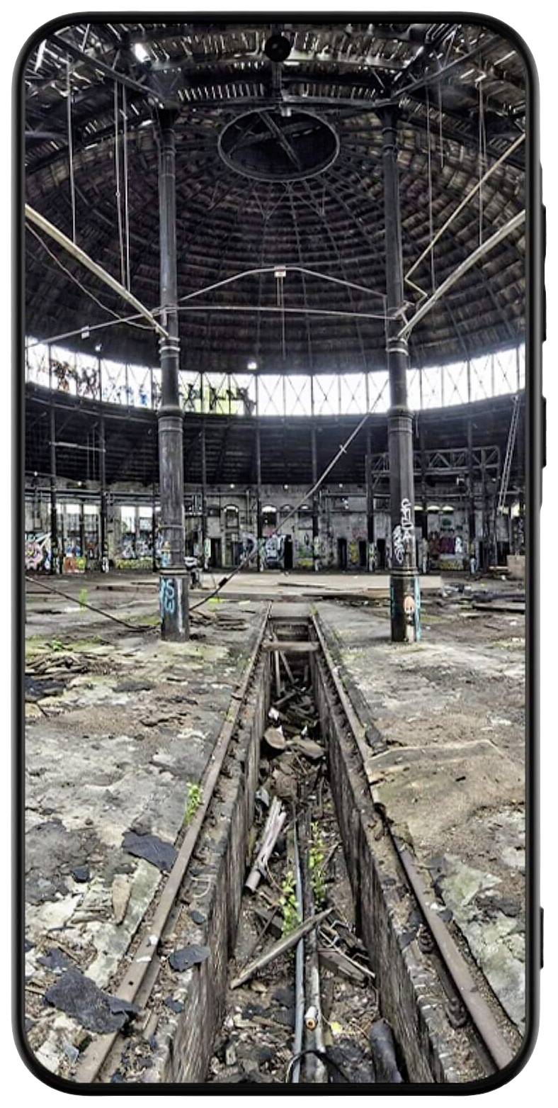 Altes, verlassenes und verfallenes Bahndepot mit einem runden Dach und sichtbaren Graffiti. Schienen verlaufen durch das Gebäude.