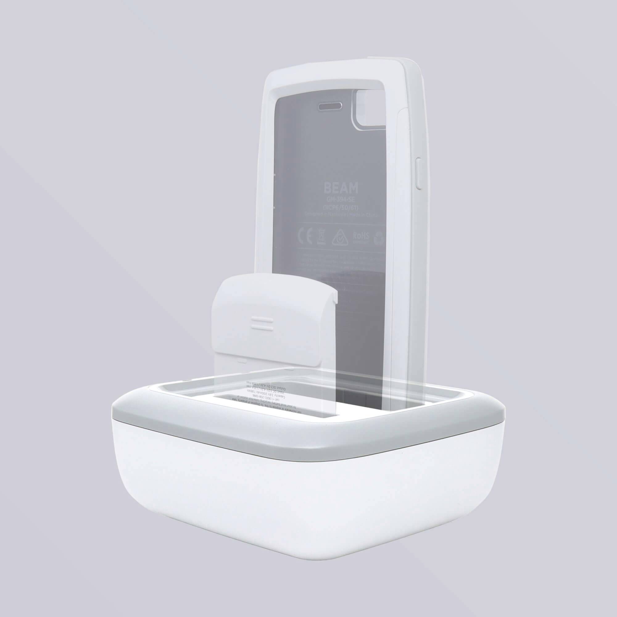 Ein weißer, quadratischer Smartphone-Desinfektionsbehälter mit transparentem Deckel, geöffnet; enthält Smartphone, Hintergrund grau.