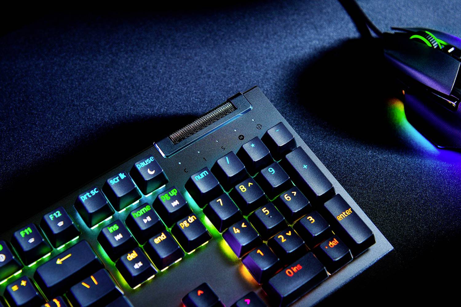 Tastatur mit RGB-Beleuchtung neben einer beleuchteten Maus auf dunklem Hintergrund.