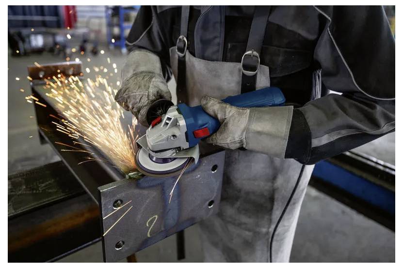 Arbeiter schleifen Metall mit einem Winkelschleifer und erzeugen dabei helle Funken in einer Industriewerkstatt.