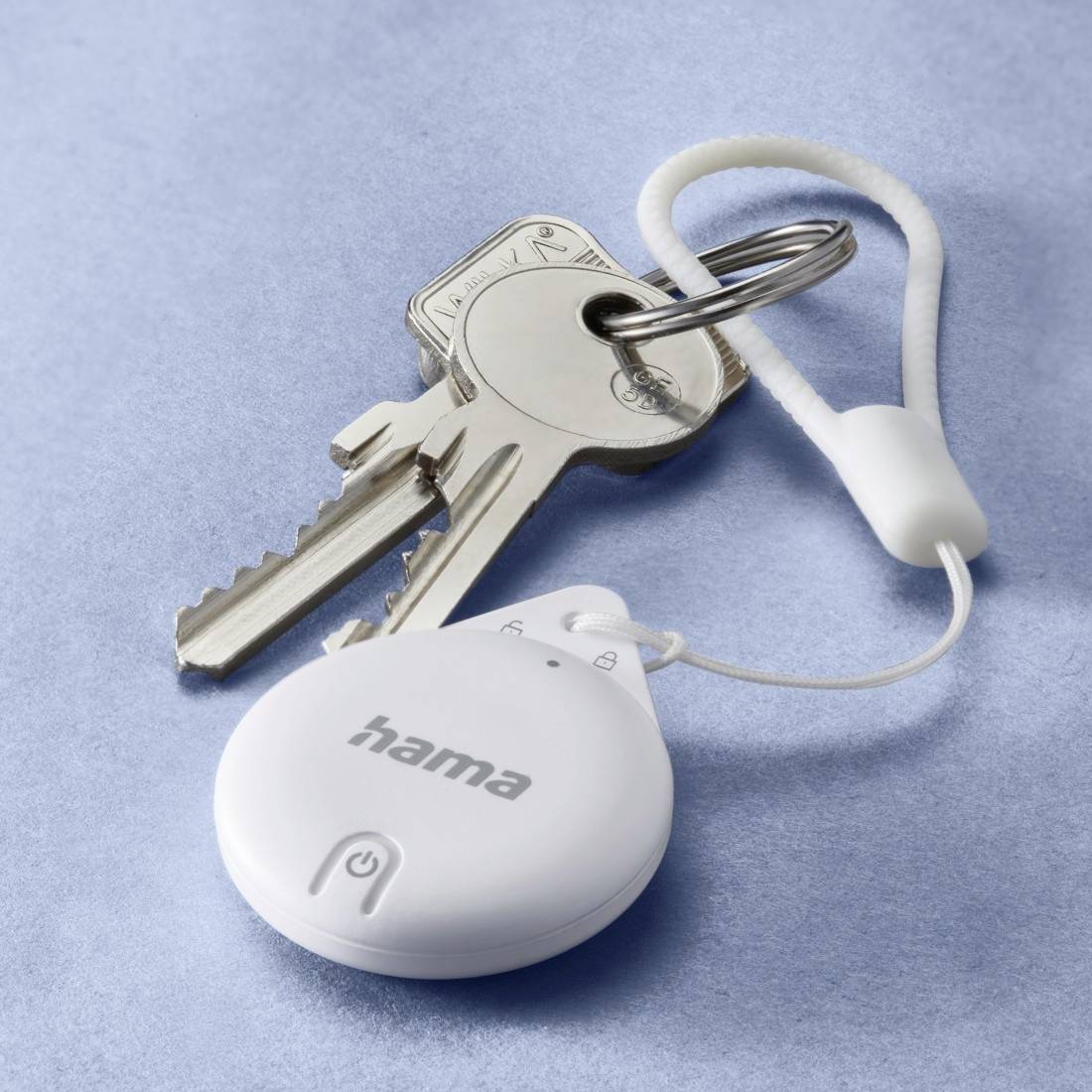 Ein kleiner, weißer Schlüssel-Finder mit 'hama'-Logo versehen, hängt an einem Schlüsselbund mit zwei Schlüsseln und einer Schlaufe.