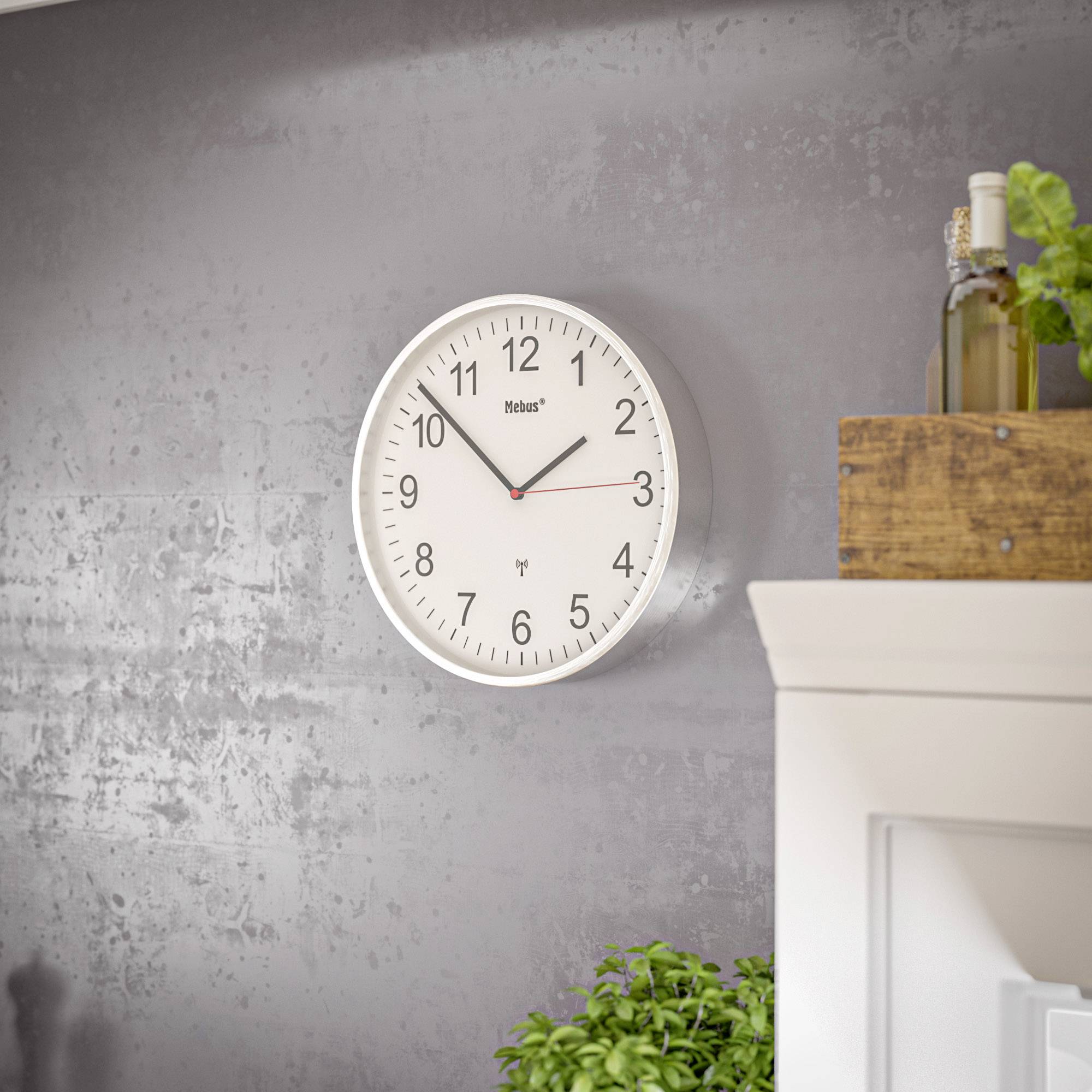 Eine analoge Wanduhr zeigt 11:54 Uhr. Links unten ist eine Pflanze sichtbar, rechts stehen Holzkästen mit grünen Flaschen darauf.