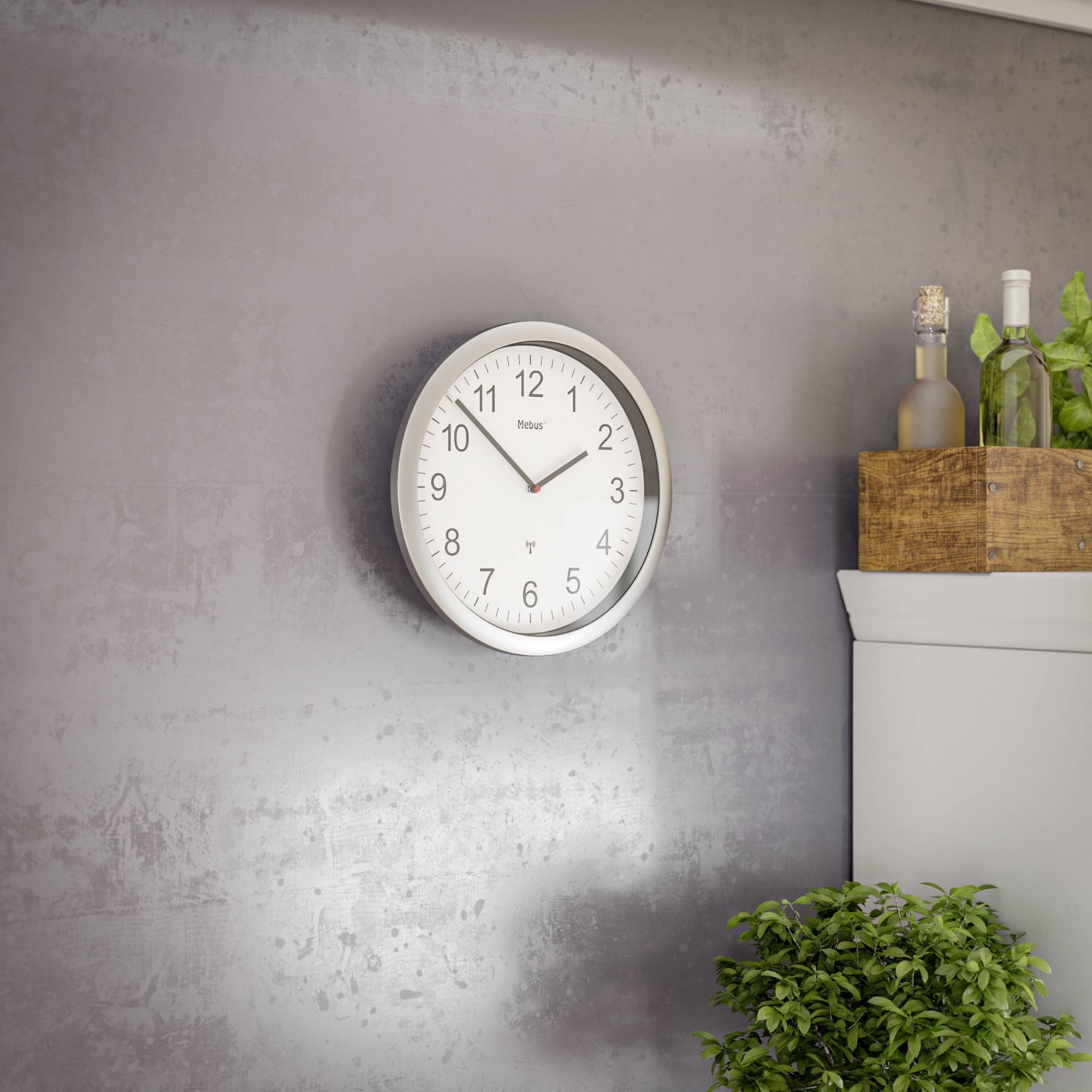 Eine Wanduhr zeigt 10:10 Uhr. Daneben steht auf einem Regal eine Holzkiste mit grünen Pflanzen, darunter eine runde Vase.
