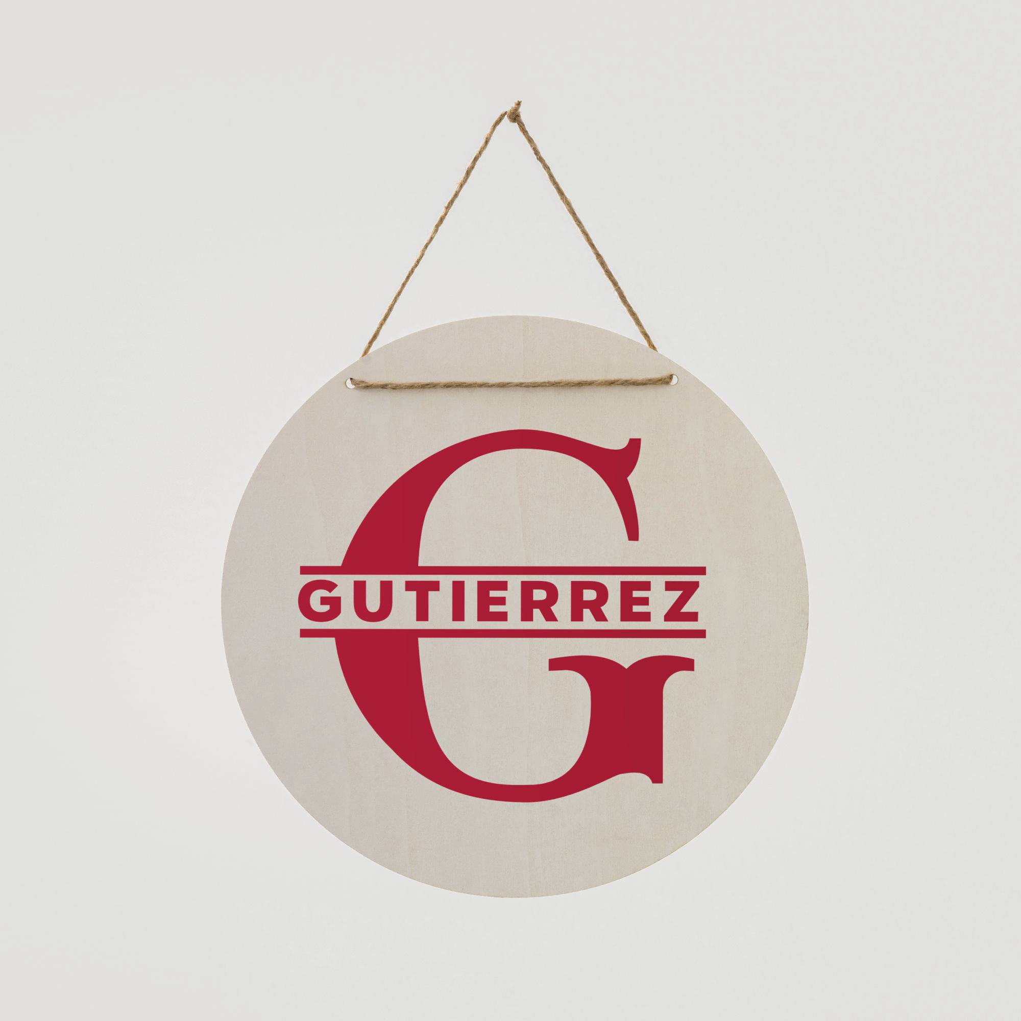 Rundes Holzschild mit rotem Buchstaben 'G' und dem darunter stehenden Namen 'Gutierrez', aufgehängt an einem Seil.