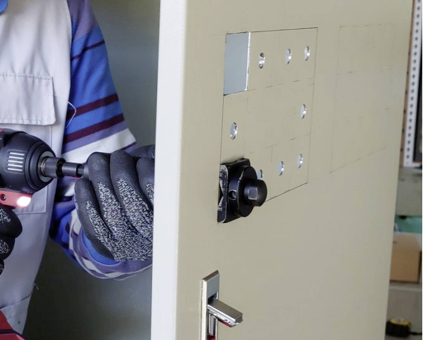 Eine Person installiert ein Sicherheitsschloss in eine Metalltür, mit einem Schraubendreher in der Hand.