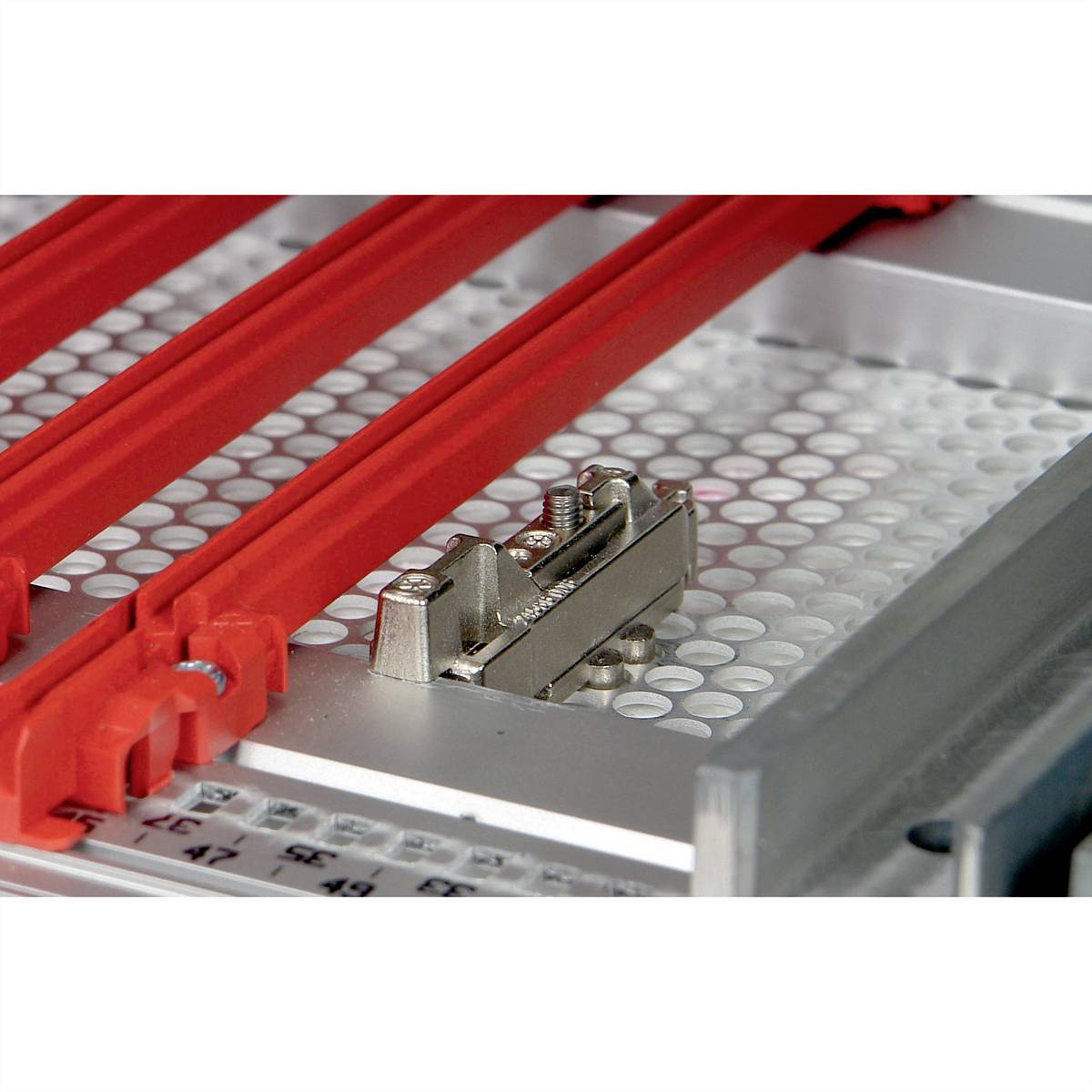 Maschine mit rot lackierten Haltevorrichtungen und Metallteilen auf einer strukturierten Oberfläche, möglicherweise für industrielle Anwendungen.