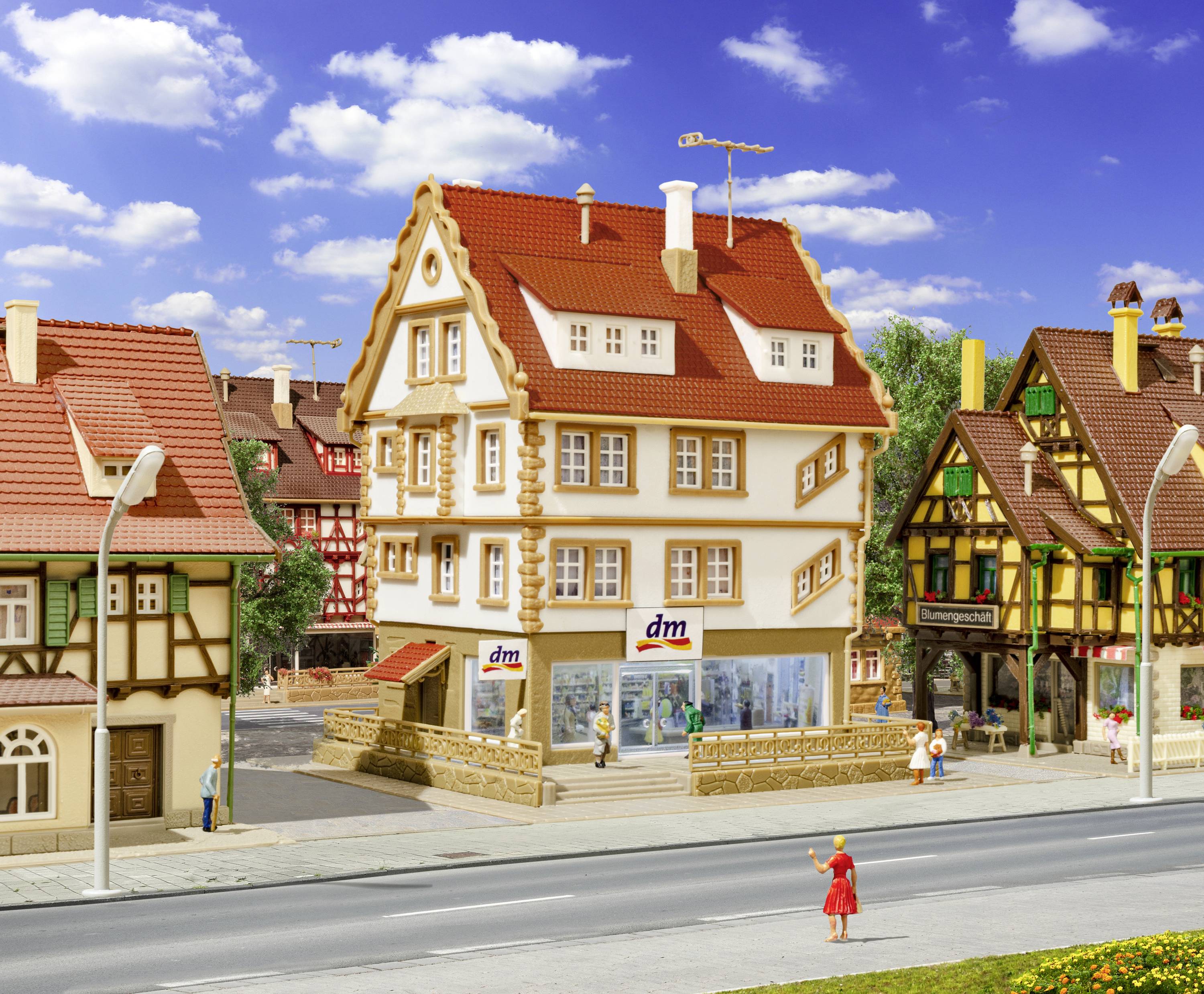 Eine Miniaturstadt mit Fachwerkhäusern, eine kleine Straße und Personen. Im Vordergrund ein Gebäude mit 'dm'-Logo.