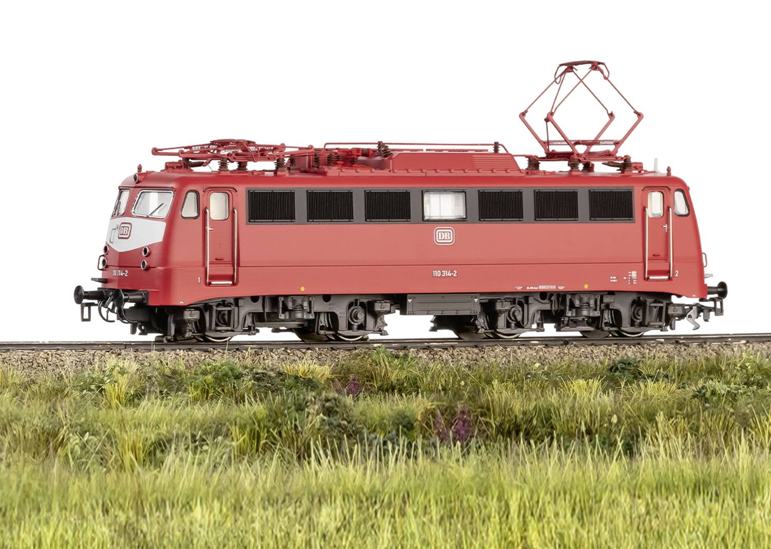 Rote Elektrolokomotive auf Gleis, seitliche Ansicht, vor grüner Wiesenlandschaft. Lokomotiven-Nummer sichtbar.