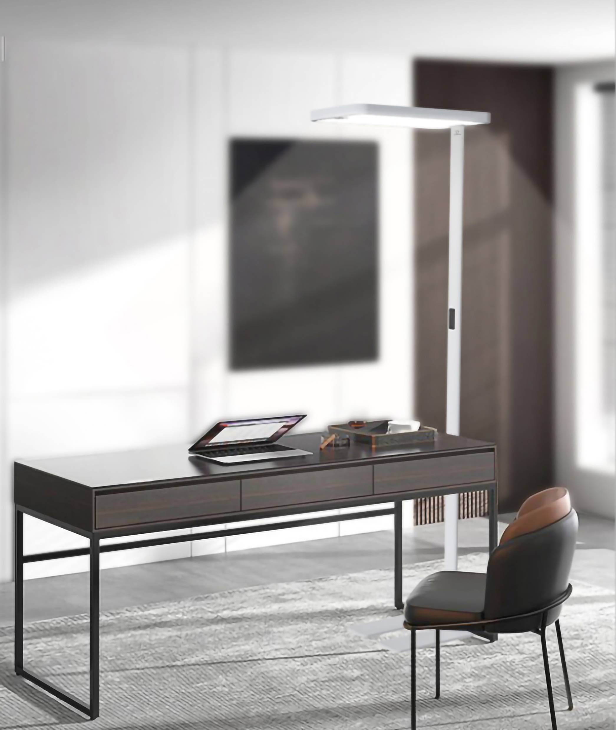 Moderner, minimalistisch eingerichteter Arbeitsbereich mit einem dunklen Schreibtisch, darauf ein Laptop und Büroartikel, daneben ein gepolsterter Stuhl.