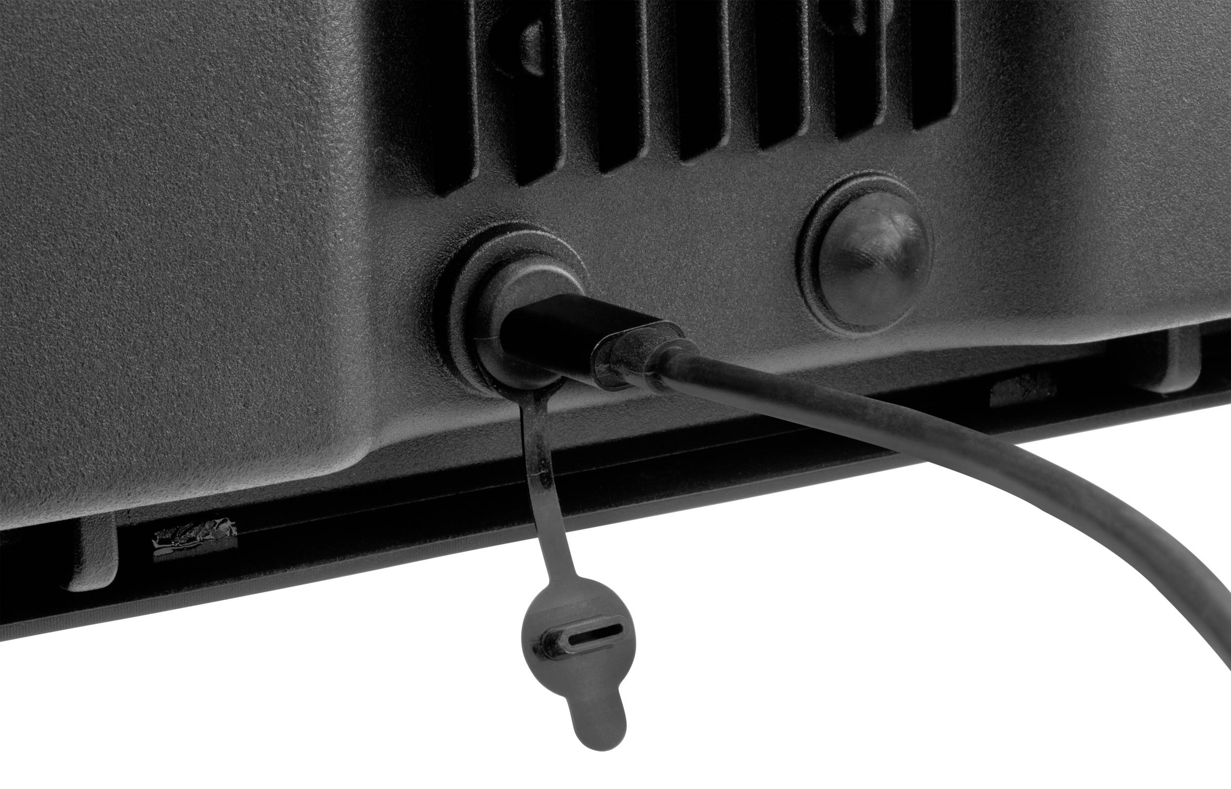 Schwarzes Kabel ist an einen Anschluss eines Elektrogeräts angeschlossen; staubgeschützter Anschluss mit abnehmbarem Verschluss.