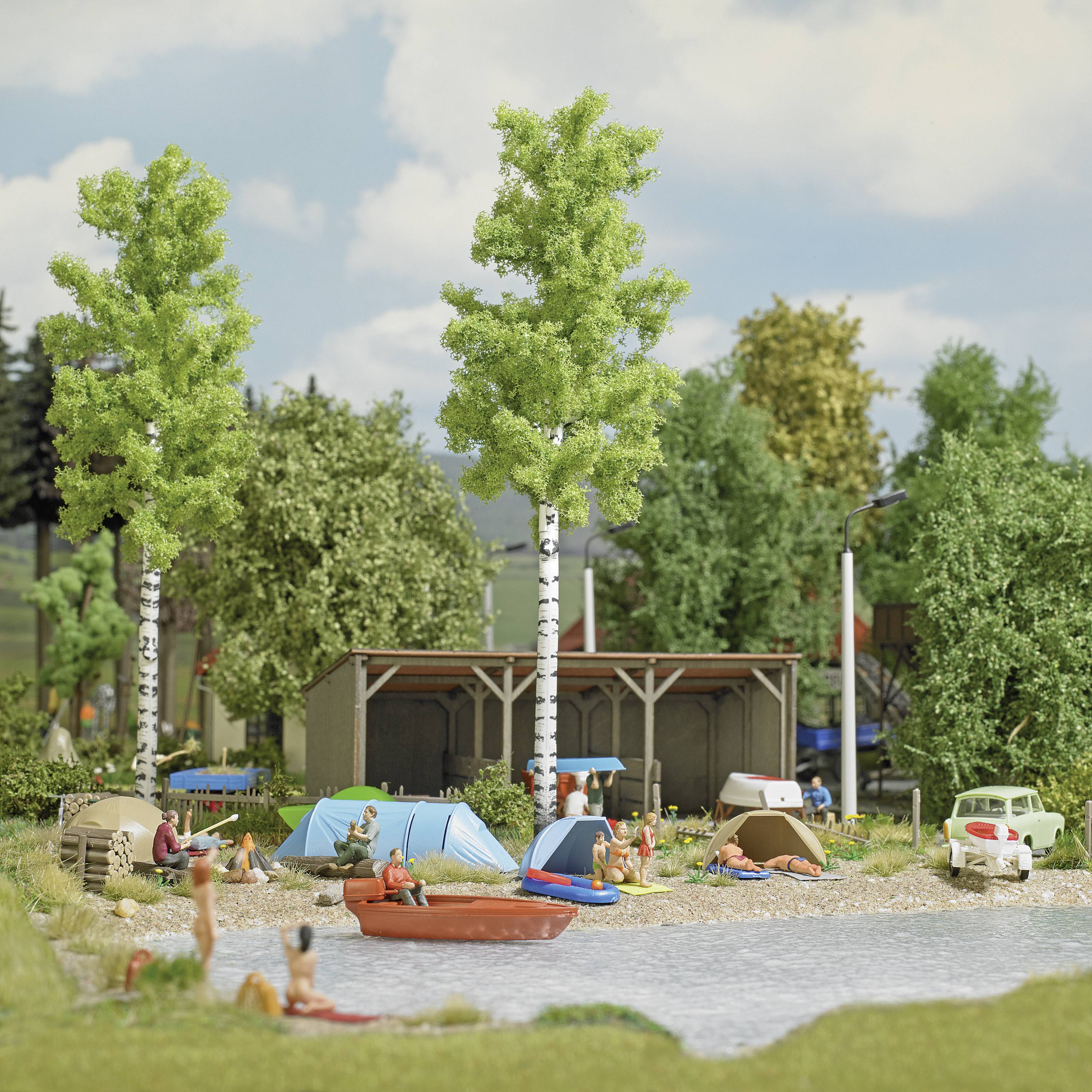 Ein Miniatur-Campingplatz mit Zelten und Wohnwagen am Seeufer. Menschen entspannen auf Liegestühlen, schwimmen und genießen die Natur.