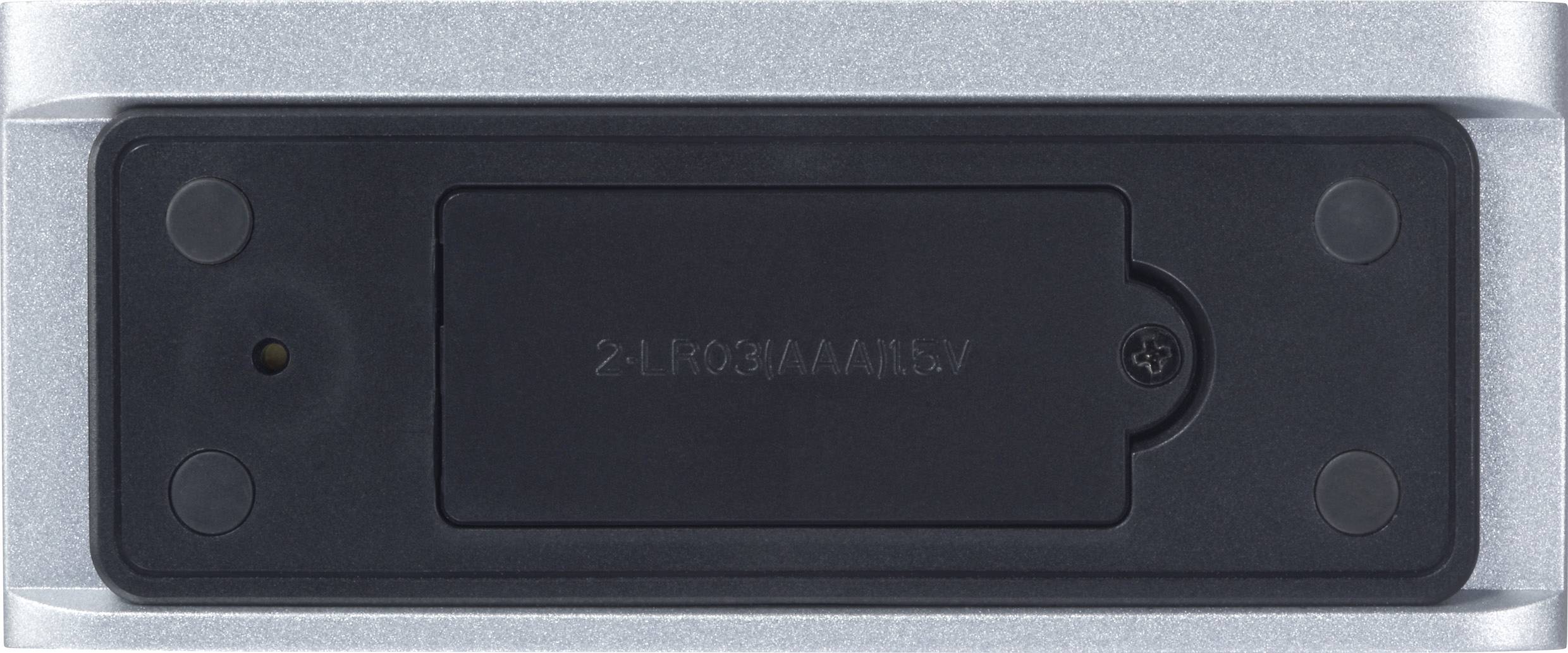 Unterseite eines Geräts mit Batteriefach und kleiner Torx-Schraube in der Mitte, umgeben von grauem Rahmen.