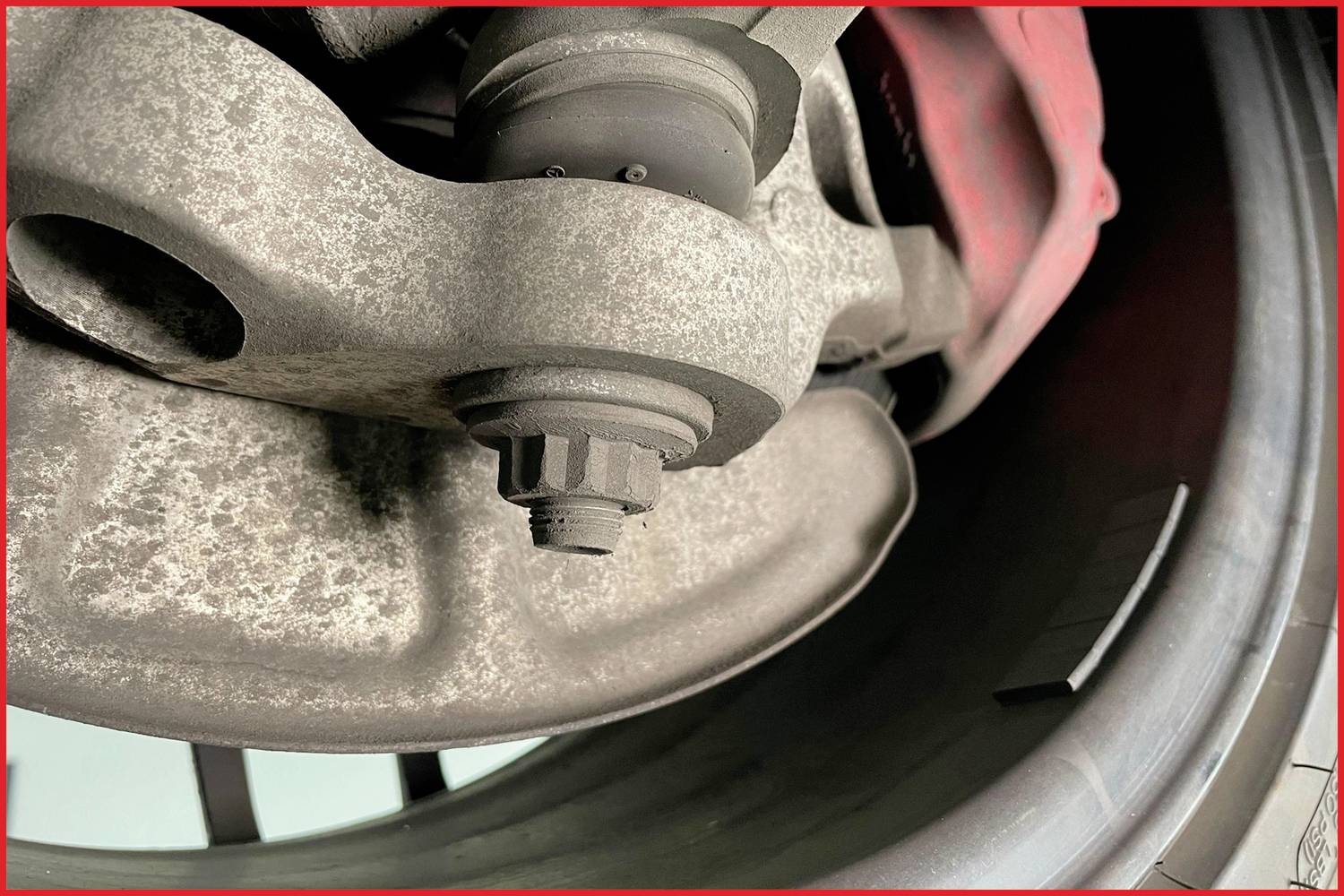 Nahaufnahme einer rostigen Radnabe eines Autos mit sichtbarem Bremssattel rechts.