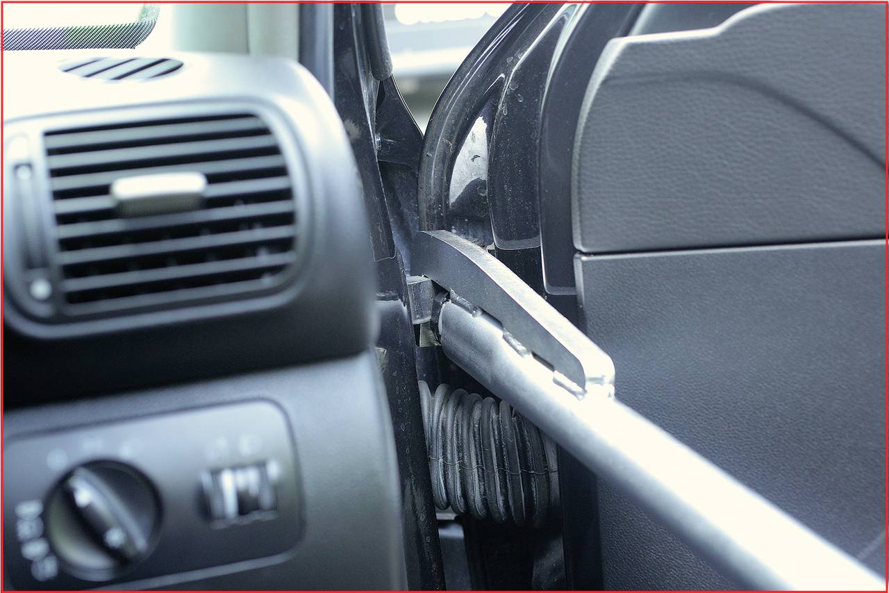 Sicherheitsvorrichtung im Auto mit Diebstahlsicherung, die die Fahrertür blockiert. Sichtbar sind Innenraumteile und Türschloss.