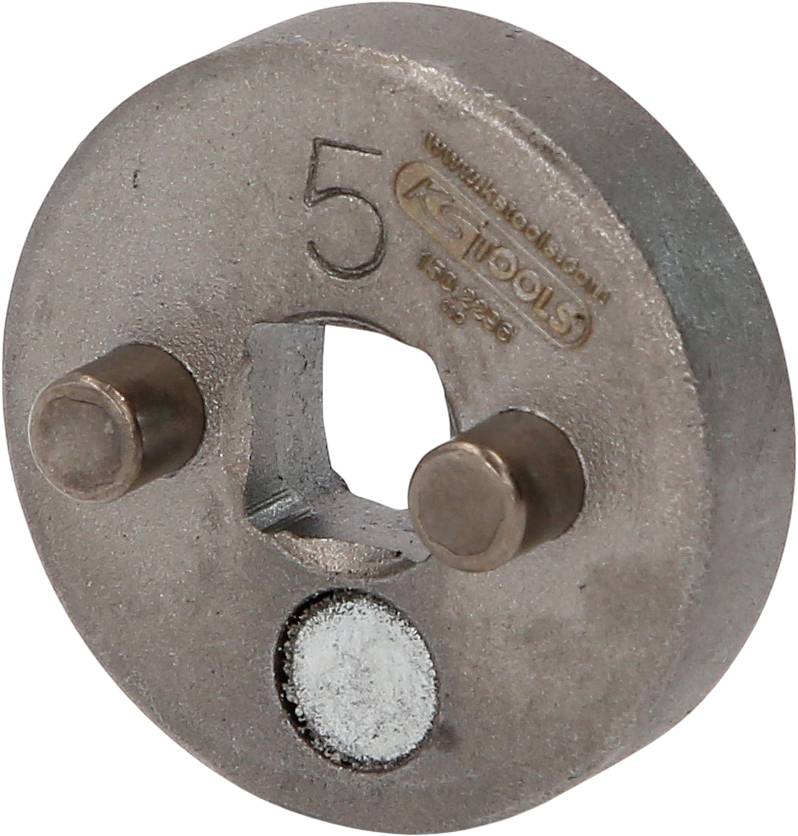 Ein rundes Metallteil mit der Aufschrift '5' und zwei herausragenden Stiften, vermutlich ein Teil eines Werkzeugs.