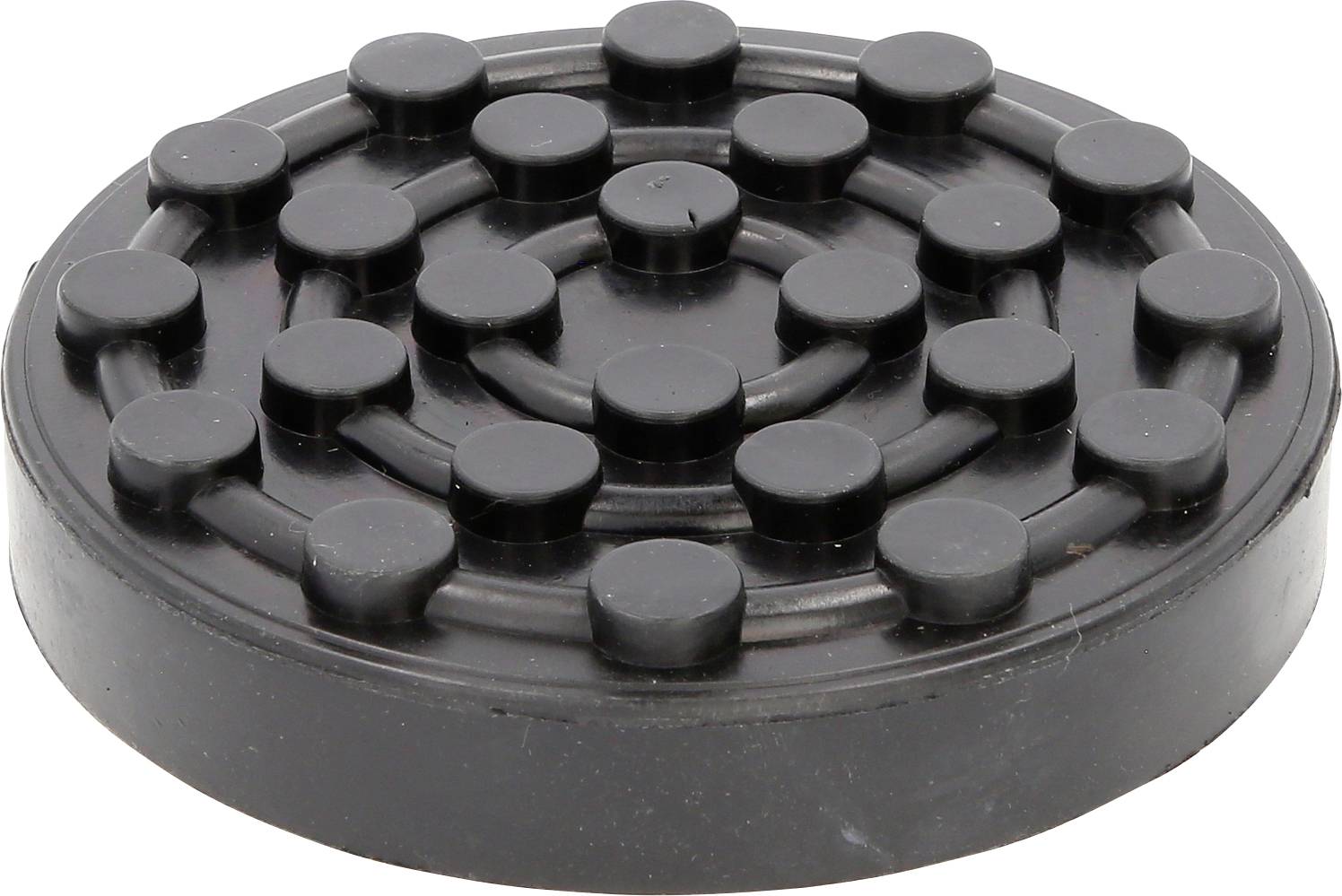 Ein schwarzer runder Gummifuß mit kreisförmig angeordneten Erhebungen, oft verwendet, um Vibrationen zu dämpfen und Oberflächen zu schützen.