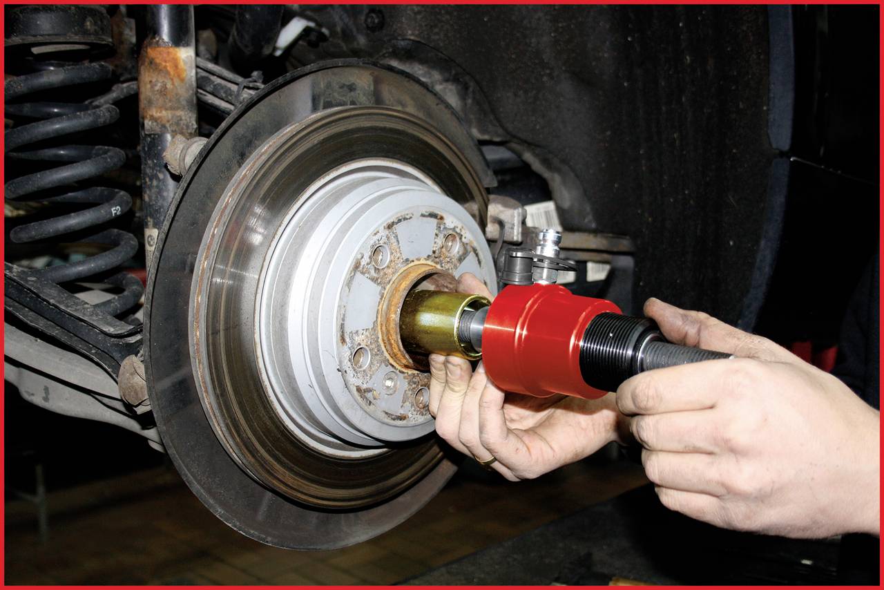 Nahaufnahme einer Autobremsanlage, bei der ein Mechaniker ein Werkzeug benutzt, um ein Teil des Bremssystems zu warten oder zu reparieren.