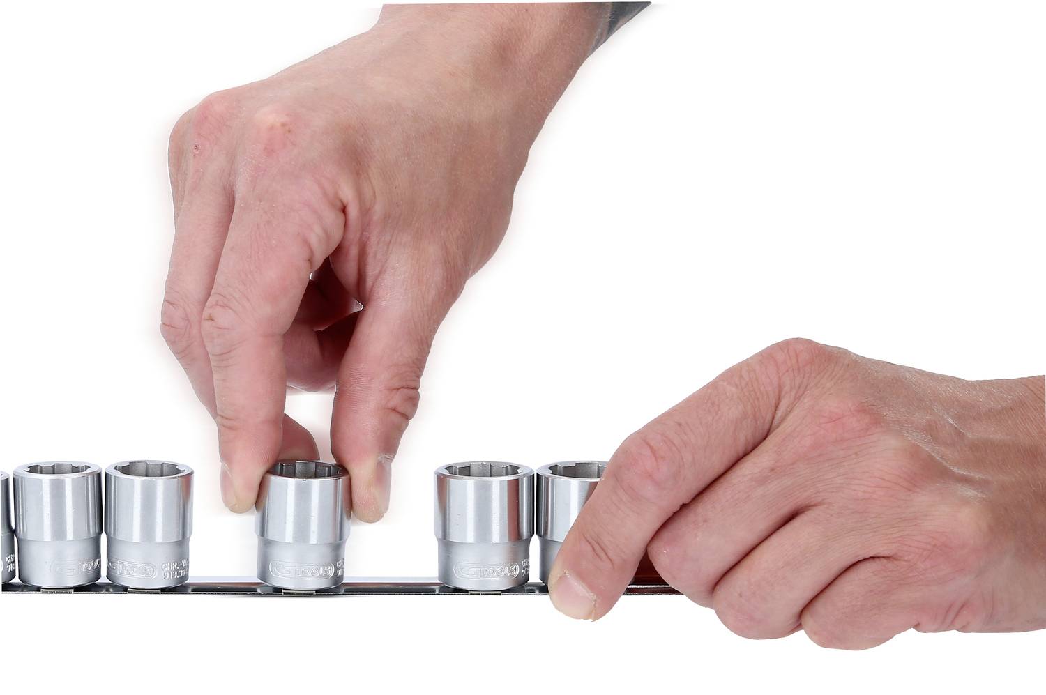 Zwei Hände greifen nach einem Steckschlüssel-Set. Die linke Hand nimmt eine Stecknuss vom Halter, während die rechte Hand den Halter festhält.