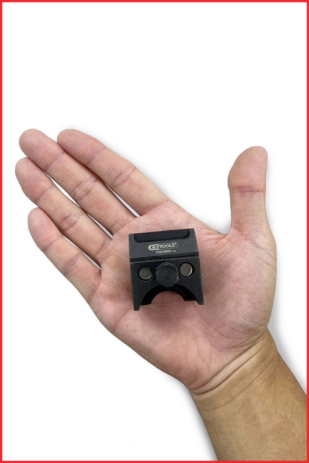 Hand hält kleines, schwarzes Metallteil mit Aufschrift 'Atlas' vor weißem Hintergrund.