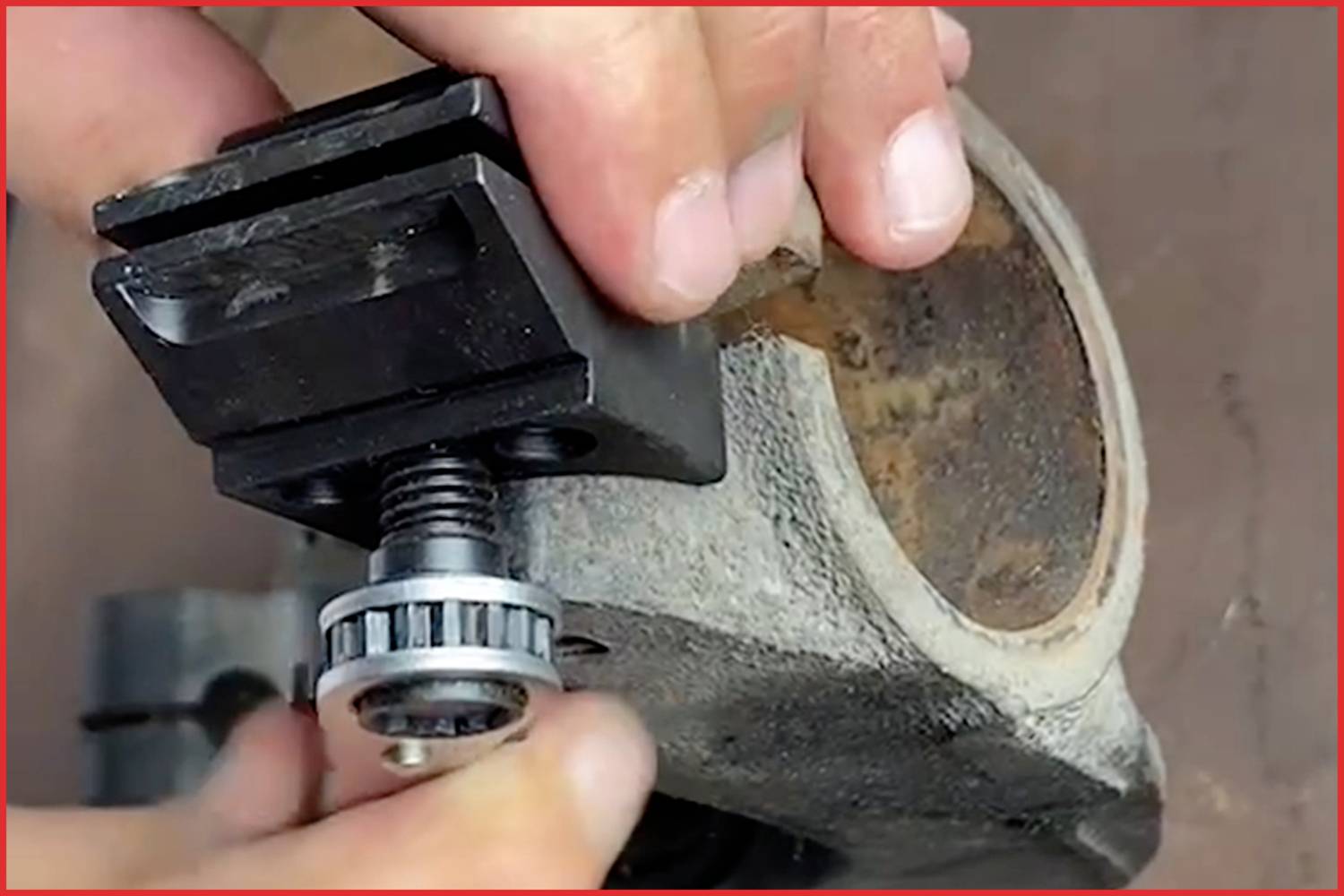 Einzelteil wird mit einer Schraube an einem Metallteil montiert. Hände justieren die Komponenten.