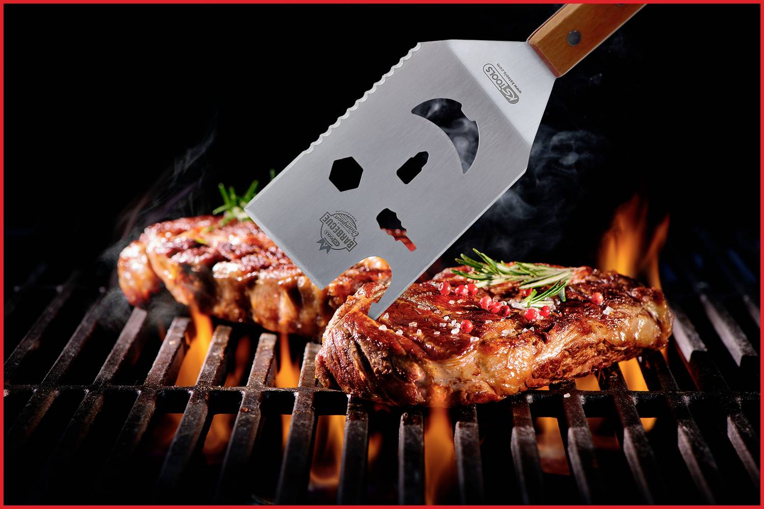 Ein Spatel hebt ein gegrilltes Steak mit Kräutern von einem Grillrost, umgeben von Flammen.