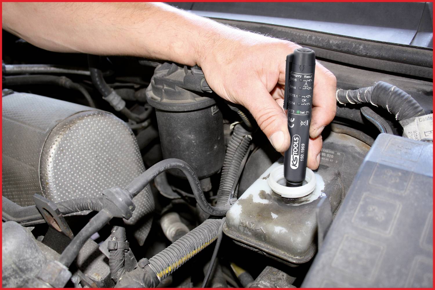 Eine Hand hält ein elektronisches Prüfgerät und testet die Bremsflüssigkeit in einem Auto.