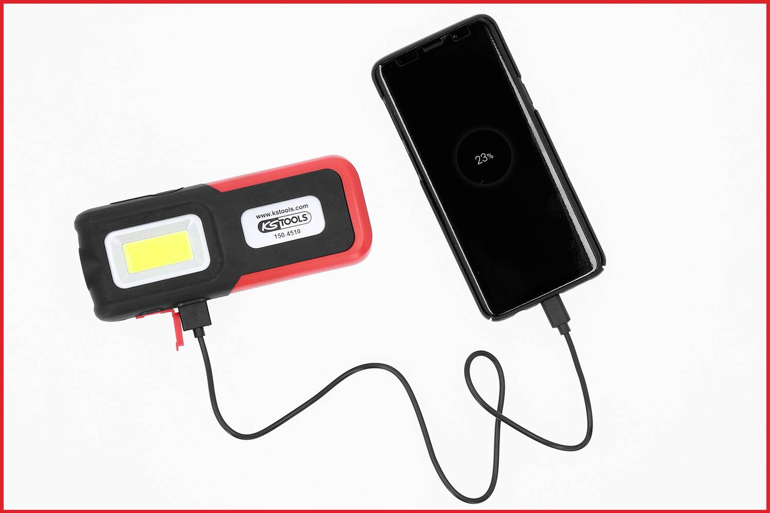 Eine tragbare Lampe mit USB-Anschluss lädt ein Smartphone auf. Das Telefon zeigt auf dem Bildschirm '23%' Ladezustand an.
