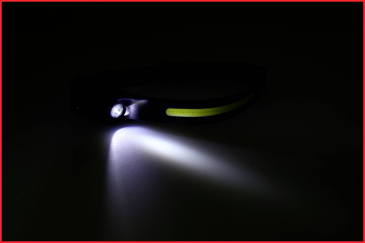 Schwarze Stirnlampe mit eingeschaltetem Licht, das einen weißen Strahl nach vorne projiziert. Dunkler Hintergrund.