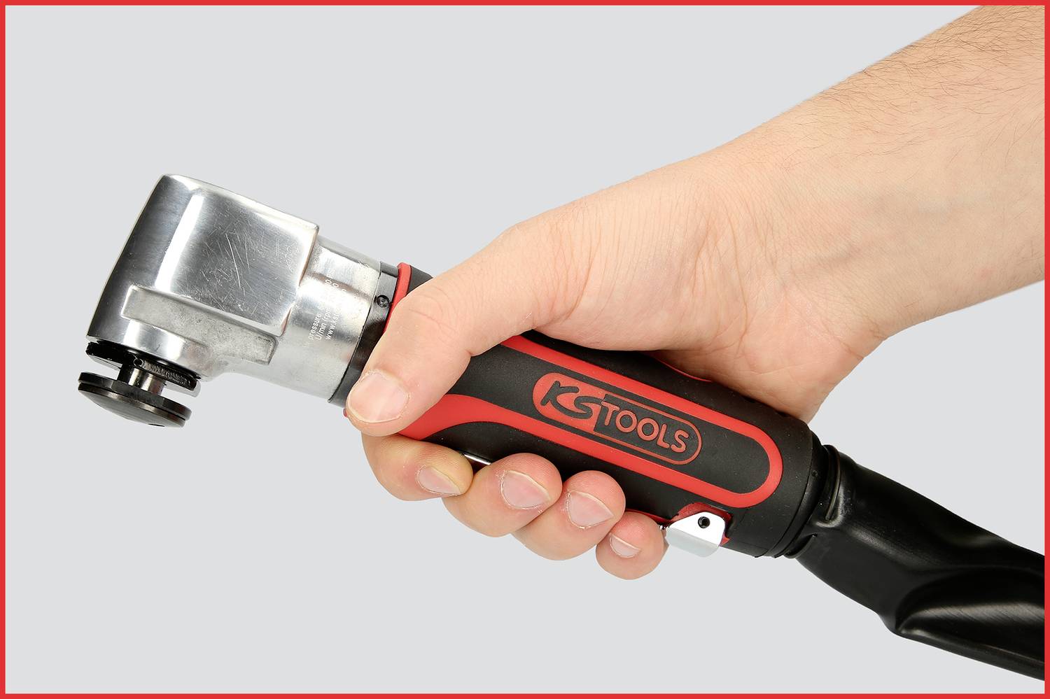 Eine Hand hält ein rot-schwarzes KS Tools Gerät mit metallischem Kopf. Das Gerät wird horizontal positioniert.