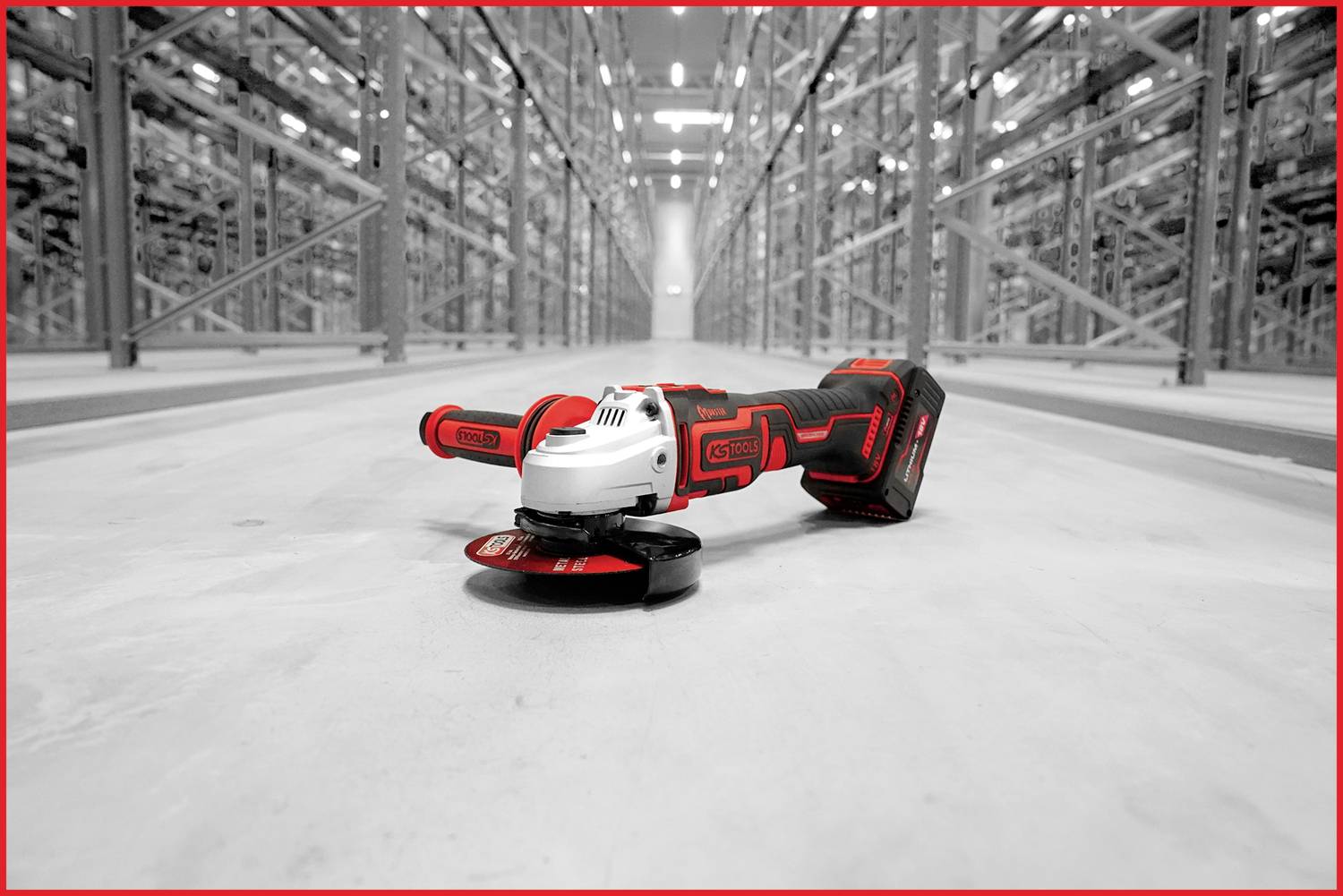 Akkubetriebener Winkelschleifer liegt auf dem Boden eines großen Industrie-Lagers, umgeben von hohen Regalen.